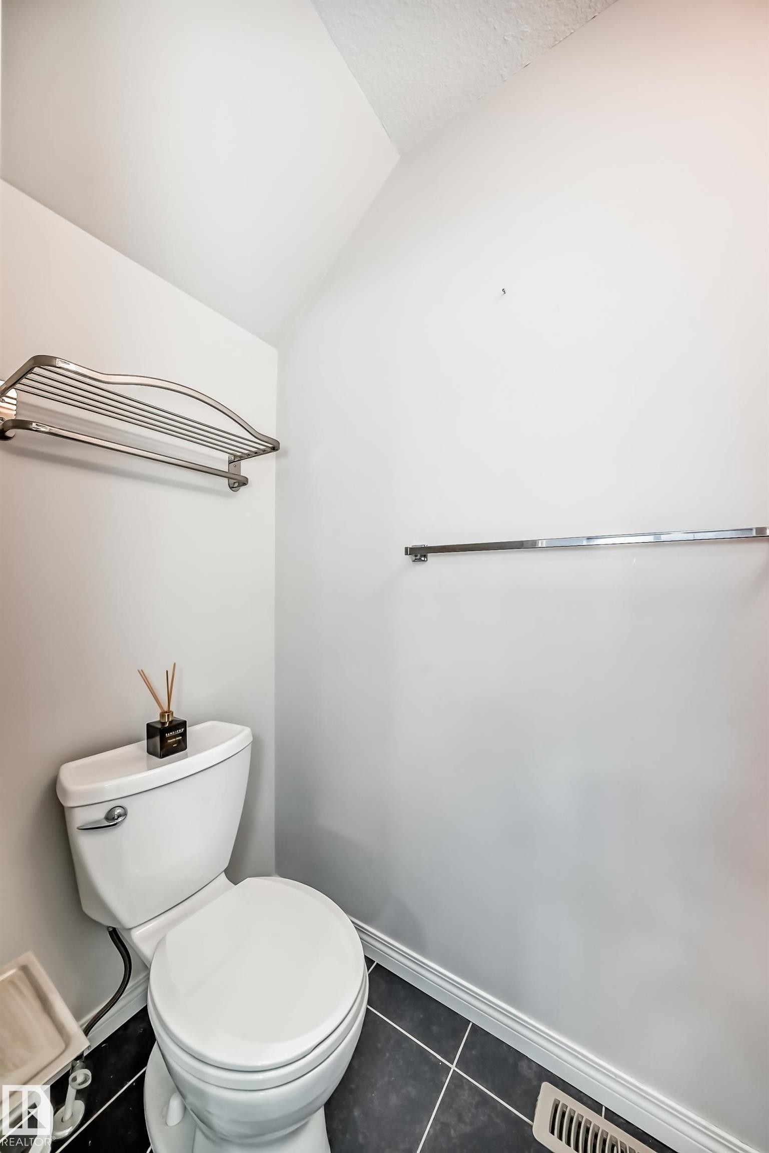 Compact bathroom featuring a white toilet, black tile flooring with white grout, and a white baseboard trim - 45 4850 Terwillegar Common, Edmonton, AB - Indoor Photo Showing Bathroom