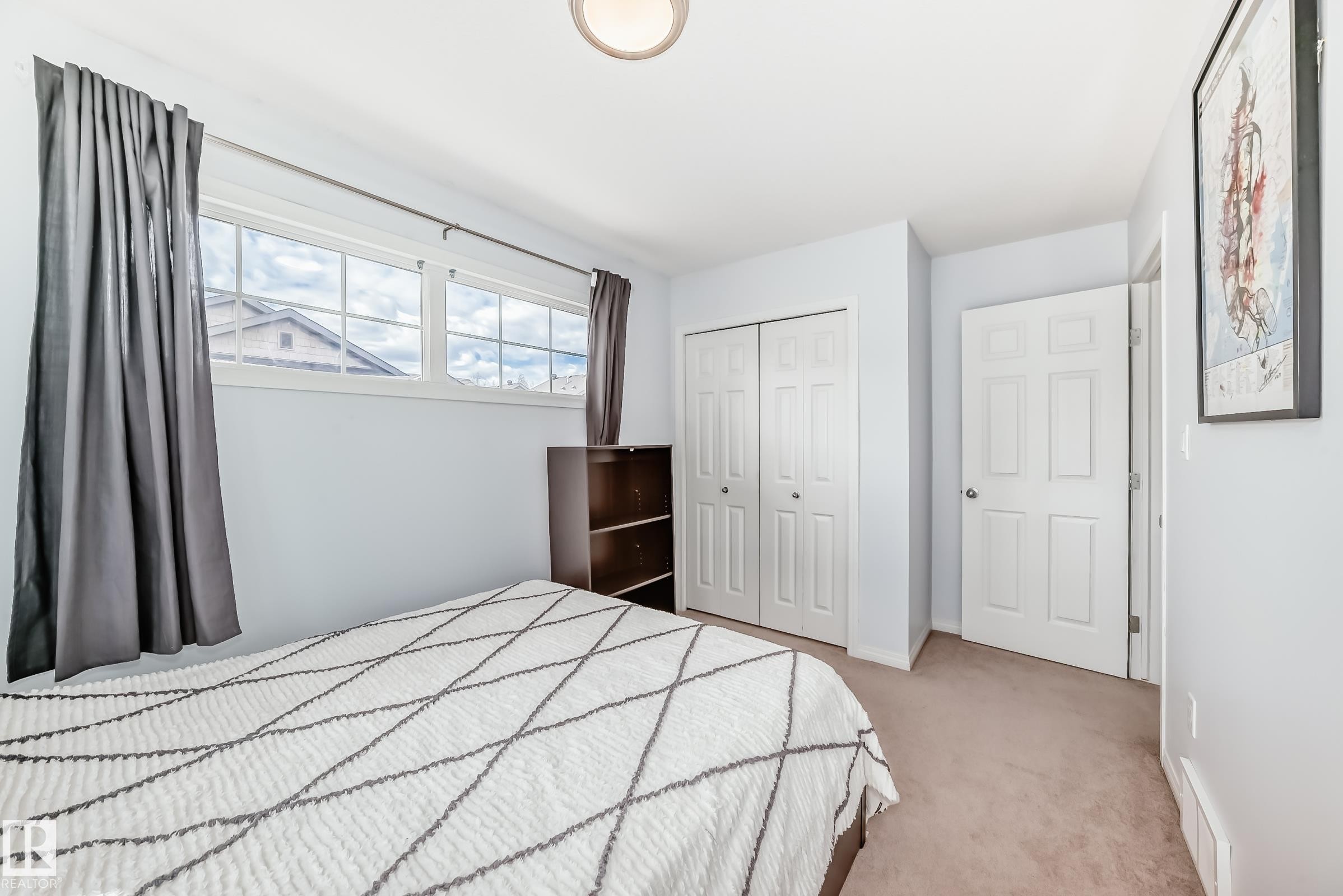 Bedroom featuring light blue walls, carpet flooring, a multi-pane window, and a flush mount ceiling light fixture - 45 4850 Terwillegar Common, Edmonton, AB - Indoor Photo Showing Bedroom