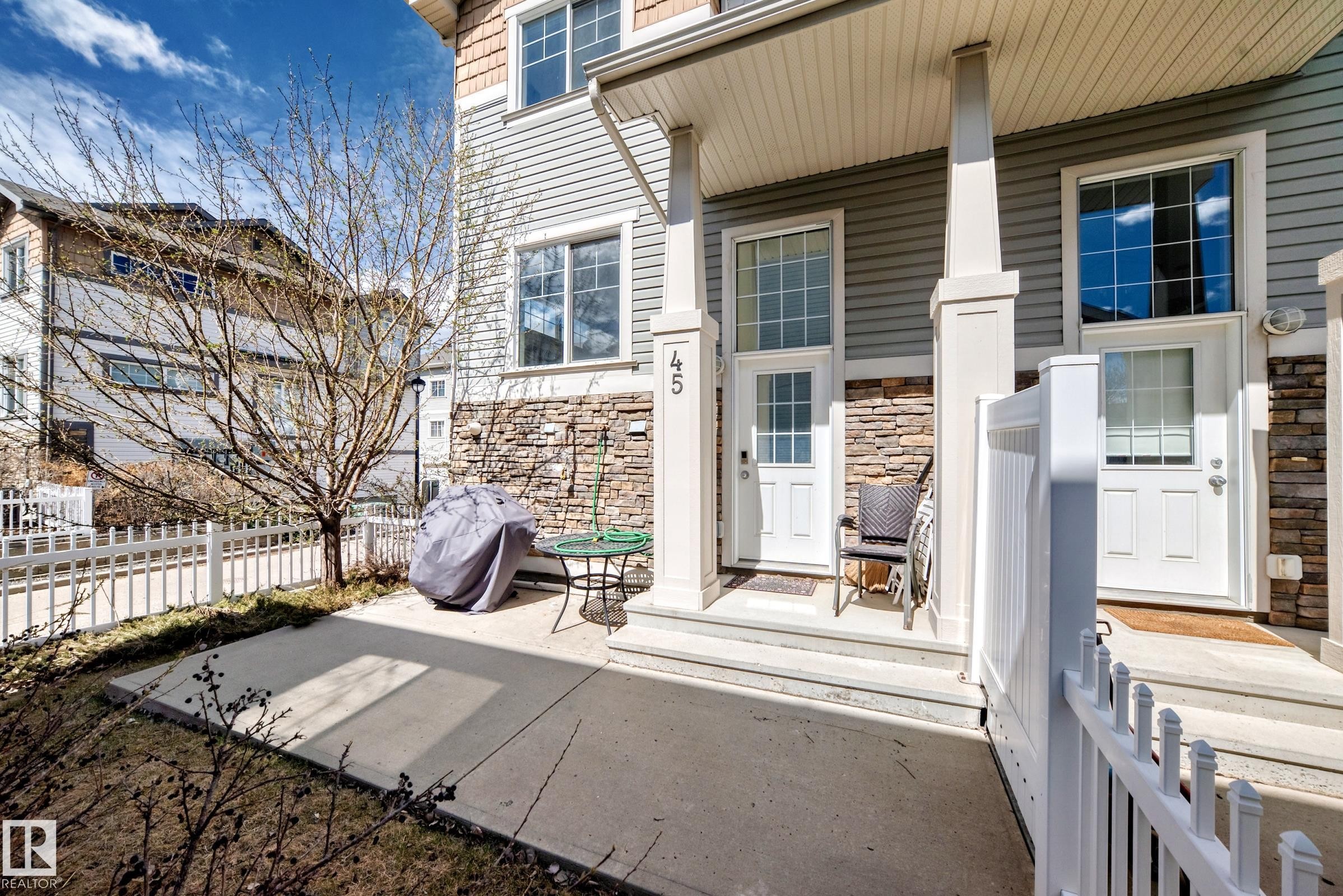 Exterior facade featuring horizontal siding, stone veneer accents, white trim, and a private patio space - 45 4850 Terwillegar Common, Edmonton, AB - Outdoor