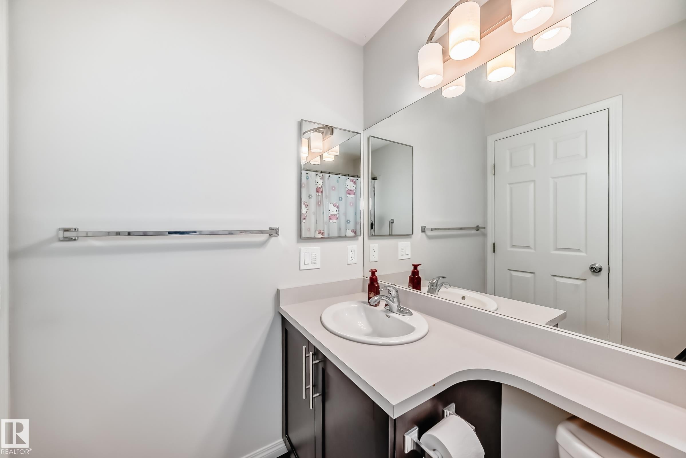 Bathroom featuring a dark wood-finish vanity with a light countertop, an integrated sink, and a chrome faucet - 45 4850 Terwillegar Common, Edmonton, AB - Indoor Photo Showing Bathroom