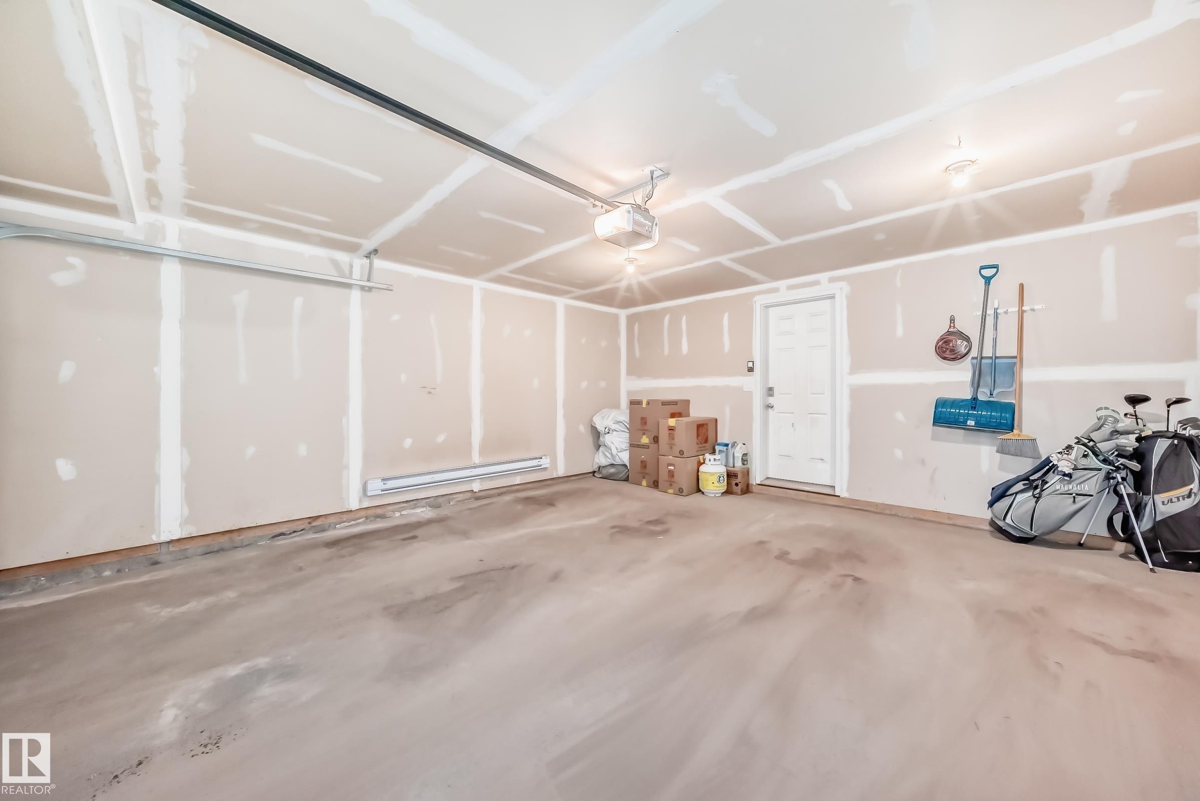 Attached two-car garage featuring exposed drywall, concrete flooring, and a side-entry door - 45 4850 Terwillegar Common, Edmonton, AB - Indoor Photo Showing Garage