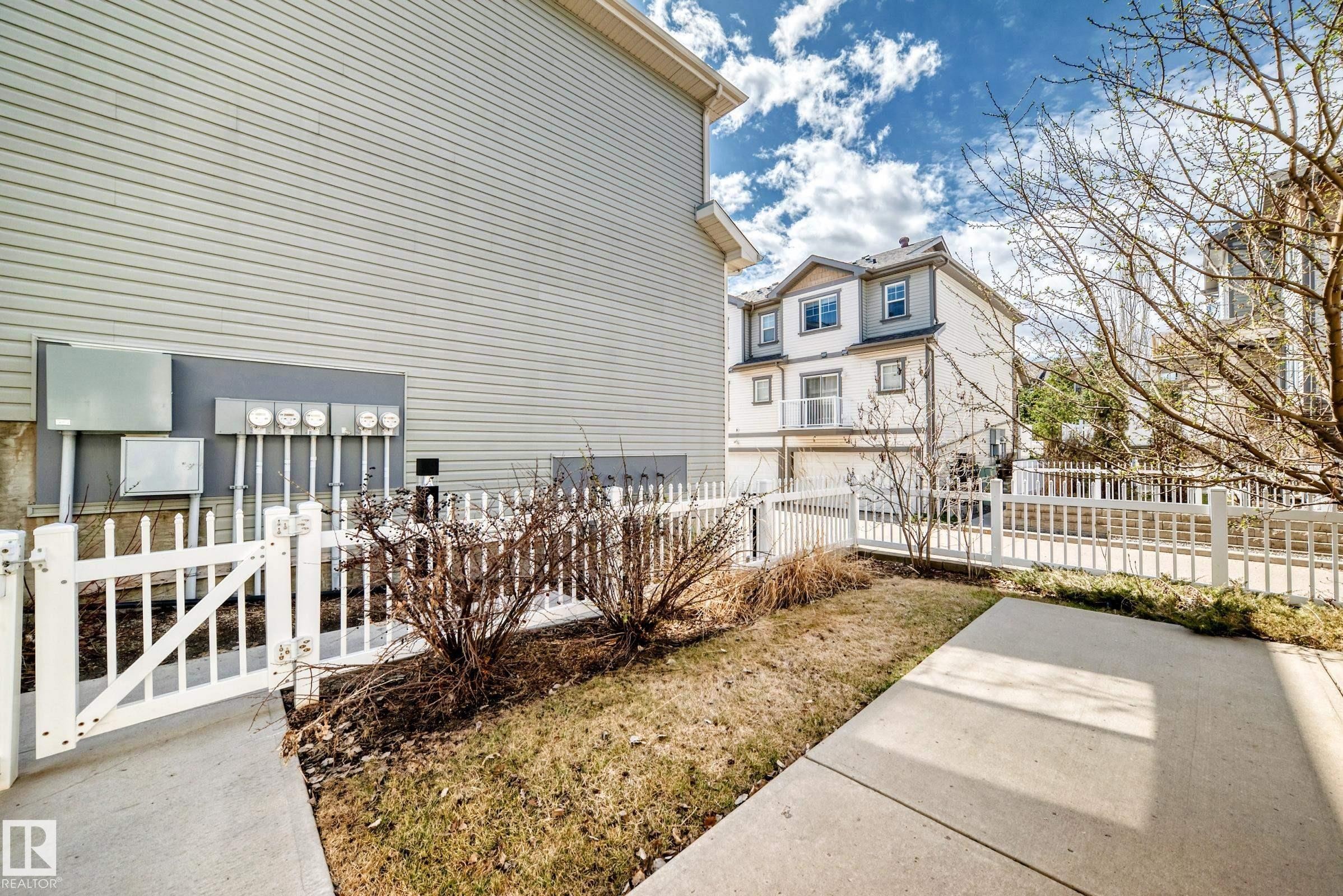 Picket fence enclosing a narrow grassy area with concrete walkway - 45 4850 Terwillegar Common, Edmonton, AB - Outdoor With Deck Patio Veranda