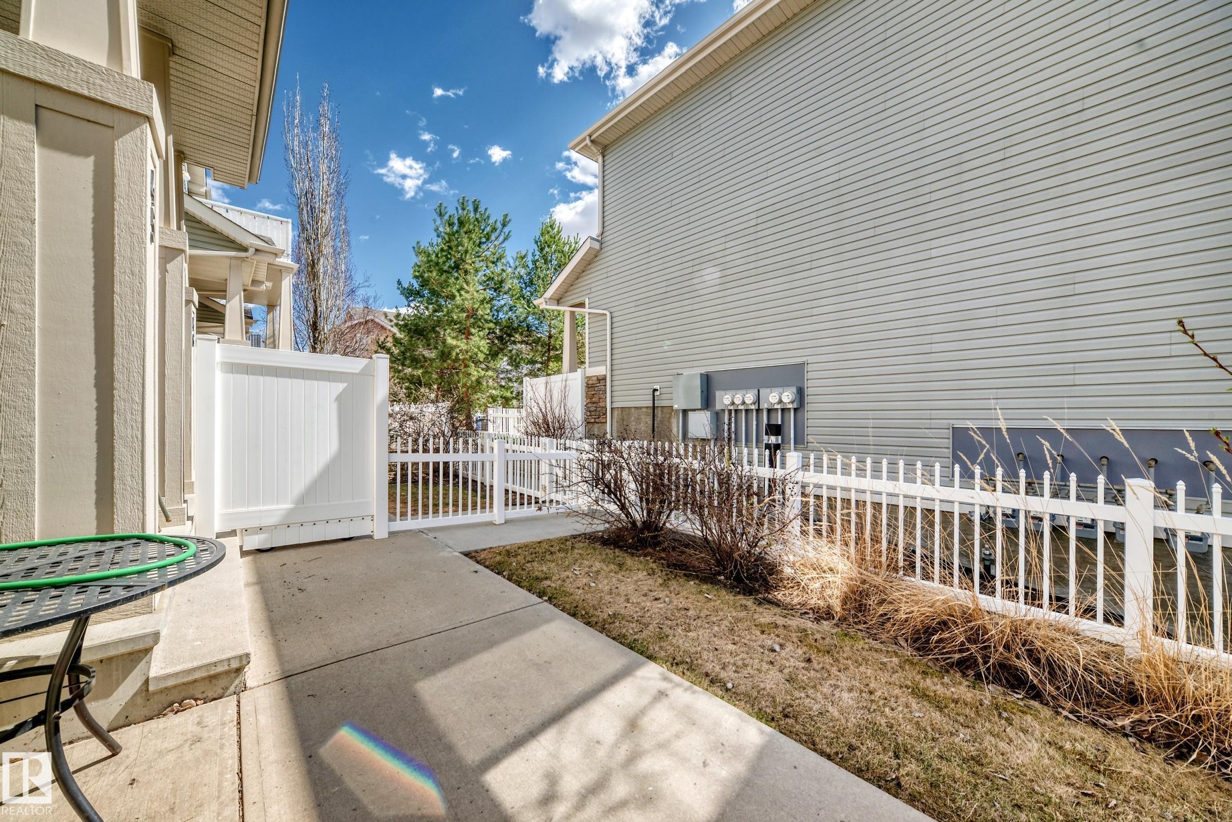 Concrete patio with a white privacy fence and picket fencing - 45 4850 Terwillegar Common, Edmonton, AB - Outdoor With Deck Patio Veranda With Exterior