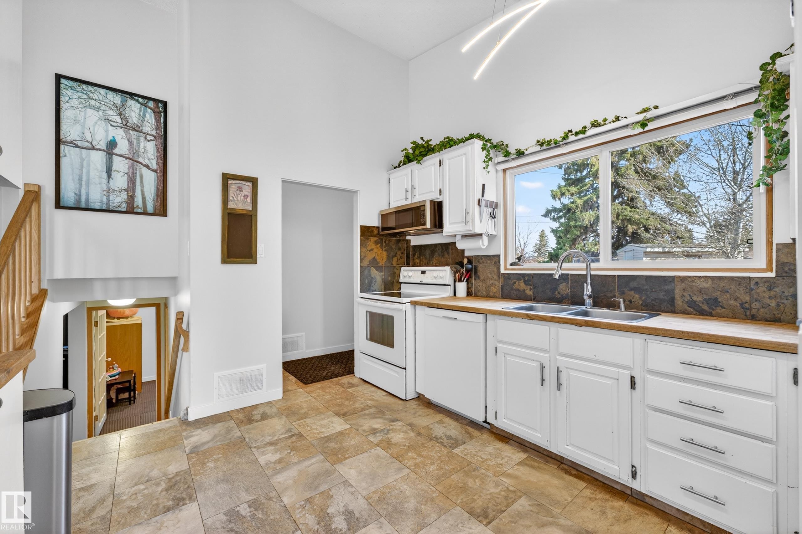 Kitchen featuring white cabinetry, wood-finish countertops, and a tile backsplash - 5304 90A Avenue, Edmonton, AB - Indoor Photo Showing Kitchen With Double Sink