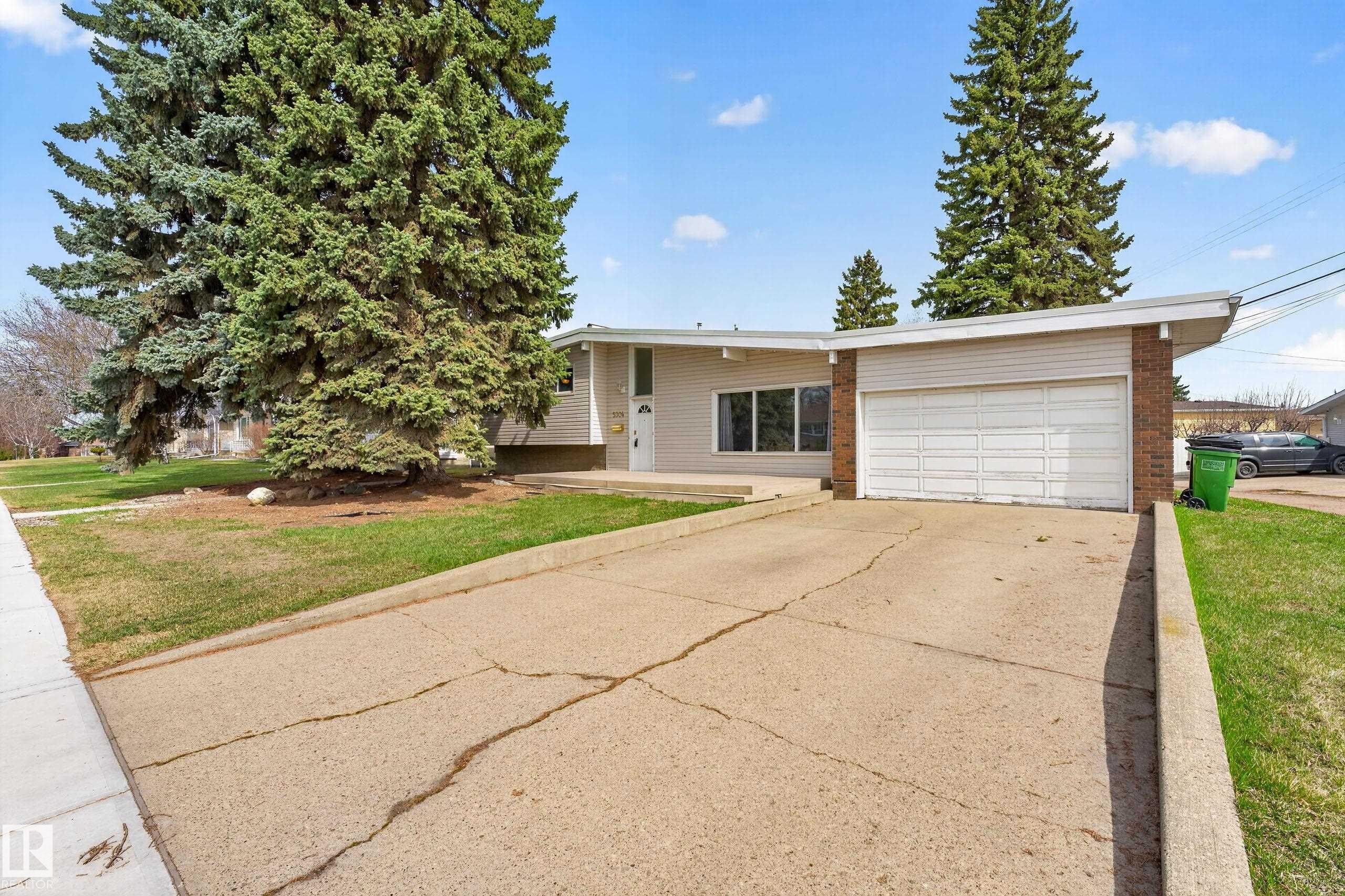 Exterior featuring a multi-pane window, white front door, and an attached two-car garage with a panel door - 5304 90A Avenue, Edmonton, AB - Outdoor