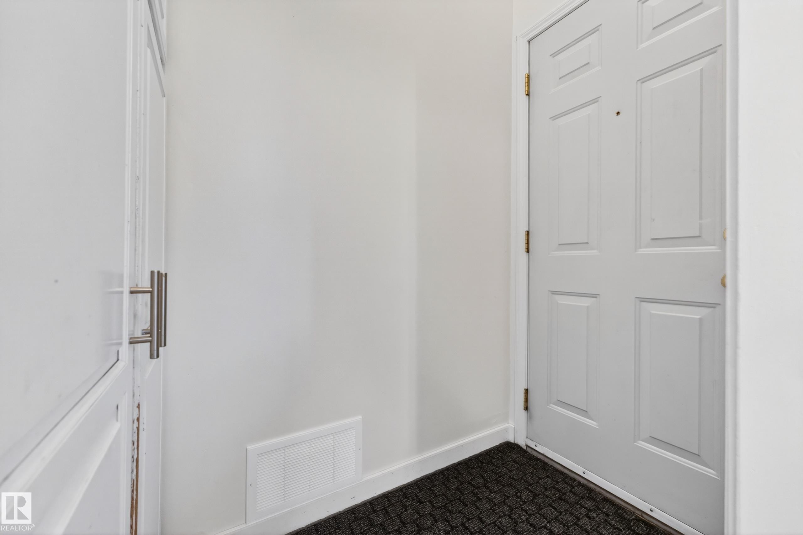 White paneled door with brass-toned hardware, featuring a black textured mat at its base - 5304 90A Avenue, Edmonton, AB - Indoor Photo Showing Other Room