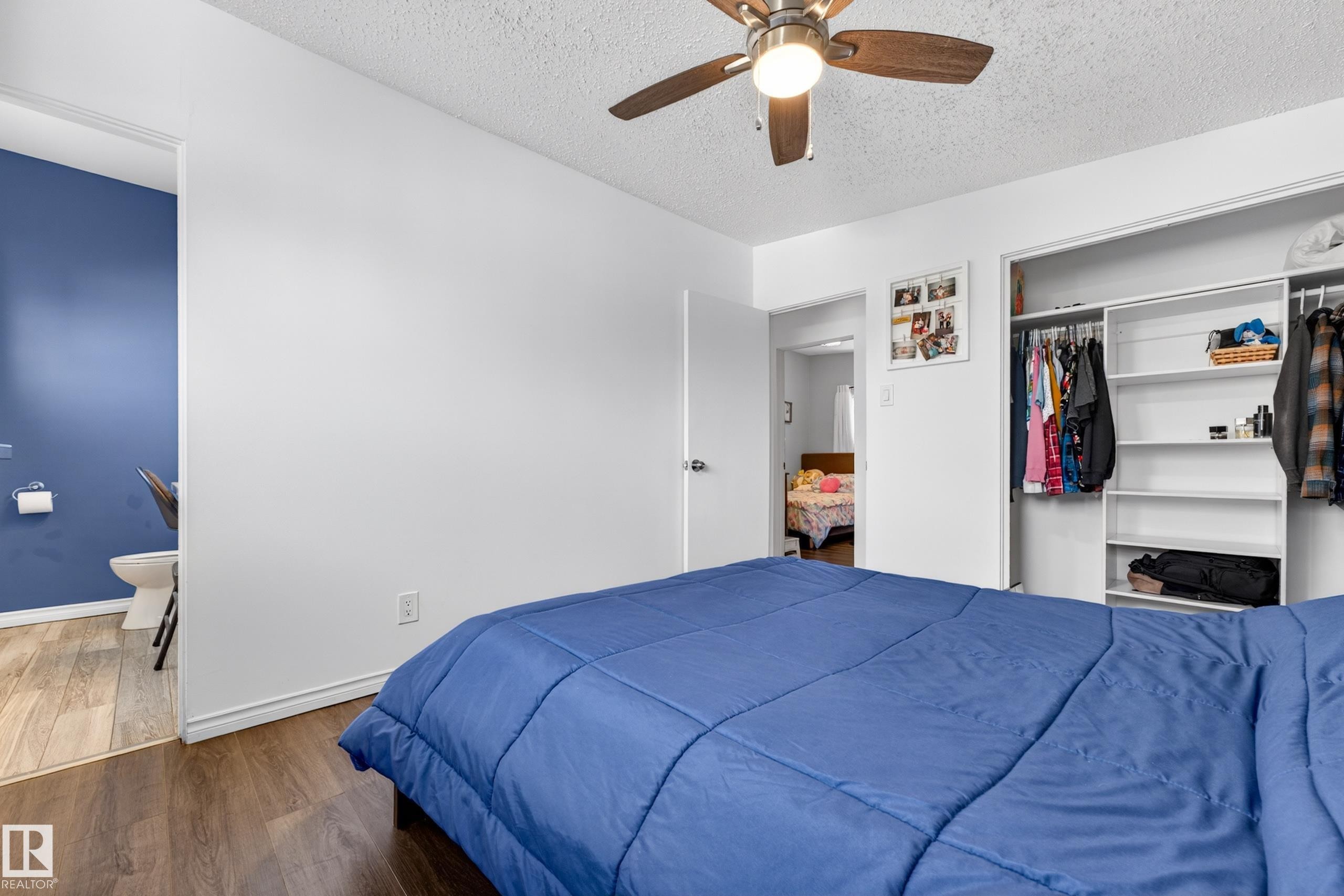 Room featuring wood-finish flooring, a ceiling fan with light fixture, and a built-in closet with shelving and hanging rods - 5304 90A Avenue, Edmonton, AB - Indoor Photo Showing Bedroom