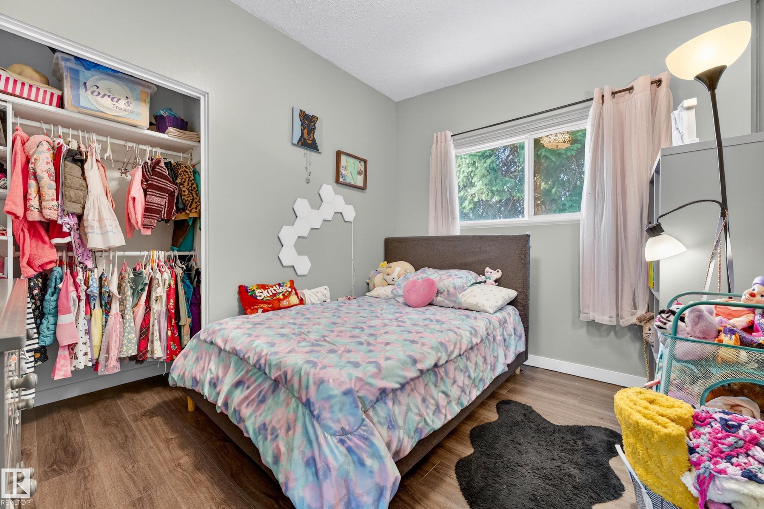 Bedroom featuring wood-finish flooring, a window with exterior tree views, and light gray wall paint - 5304 90A Avenue, Edmonton, AB - Indoor Photo Showing Bedroom