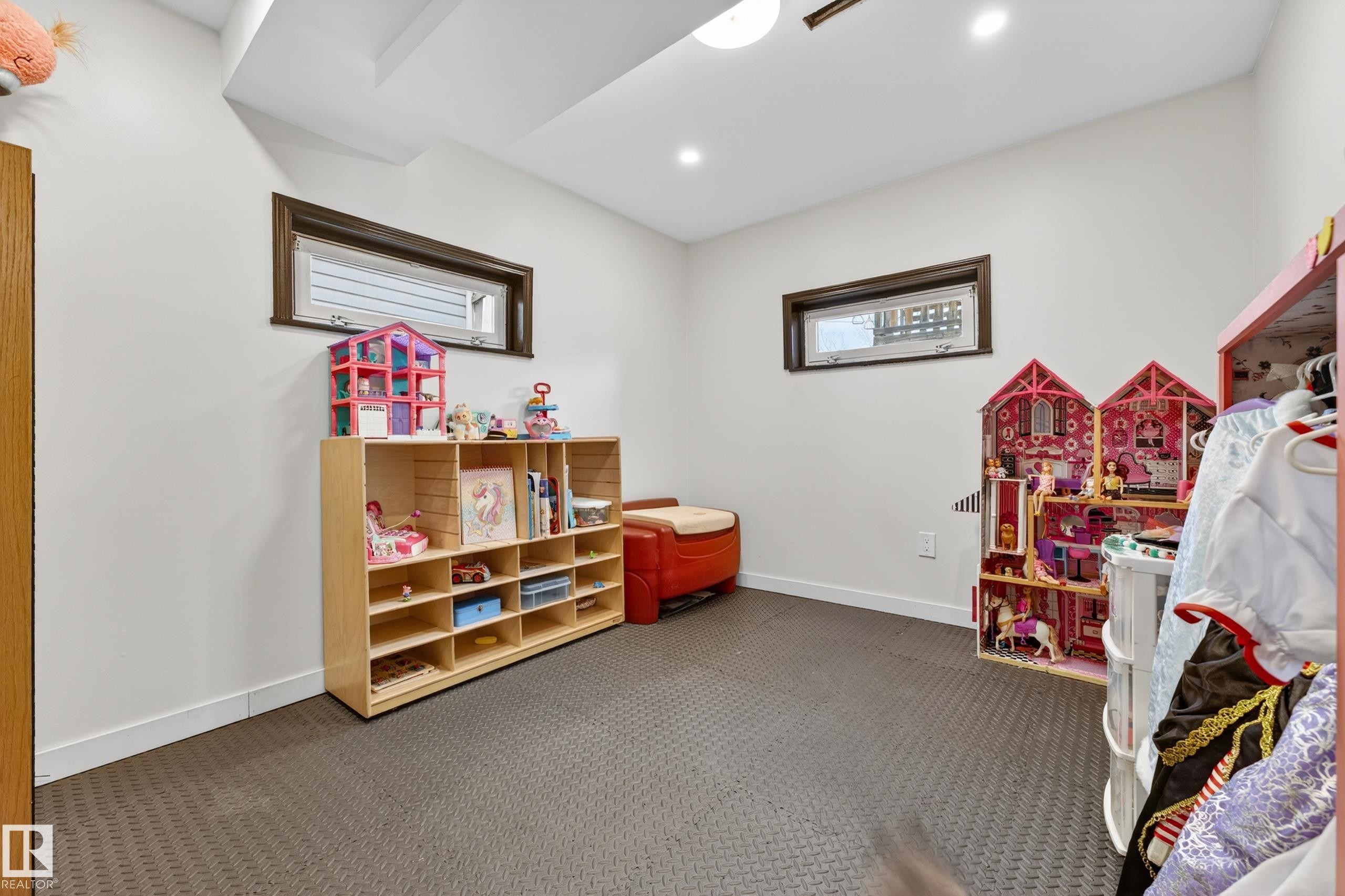Recessed lighting illuminates this versatile room with dark-framed windows and textured flooring - 5304 90A Avenue, Edmonton, AB - Indoor