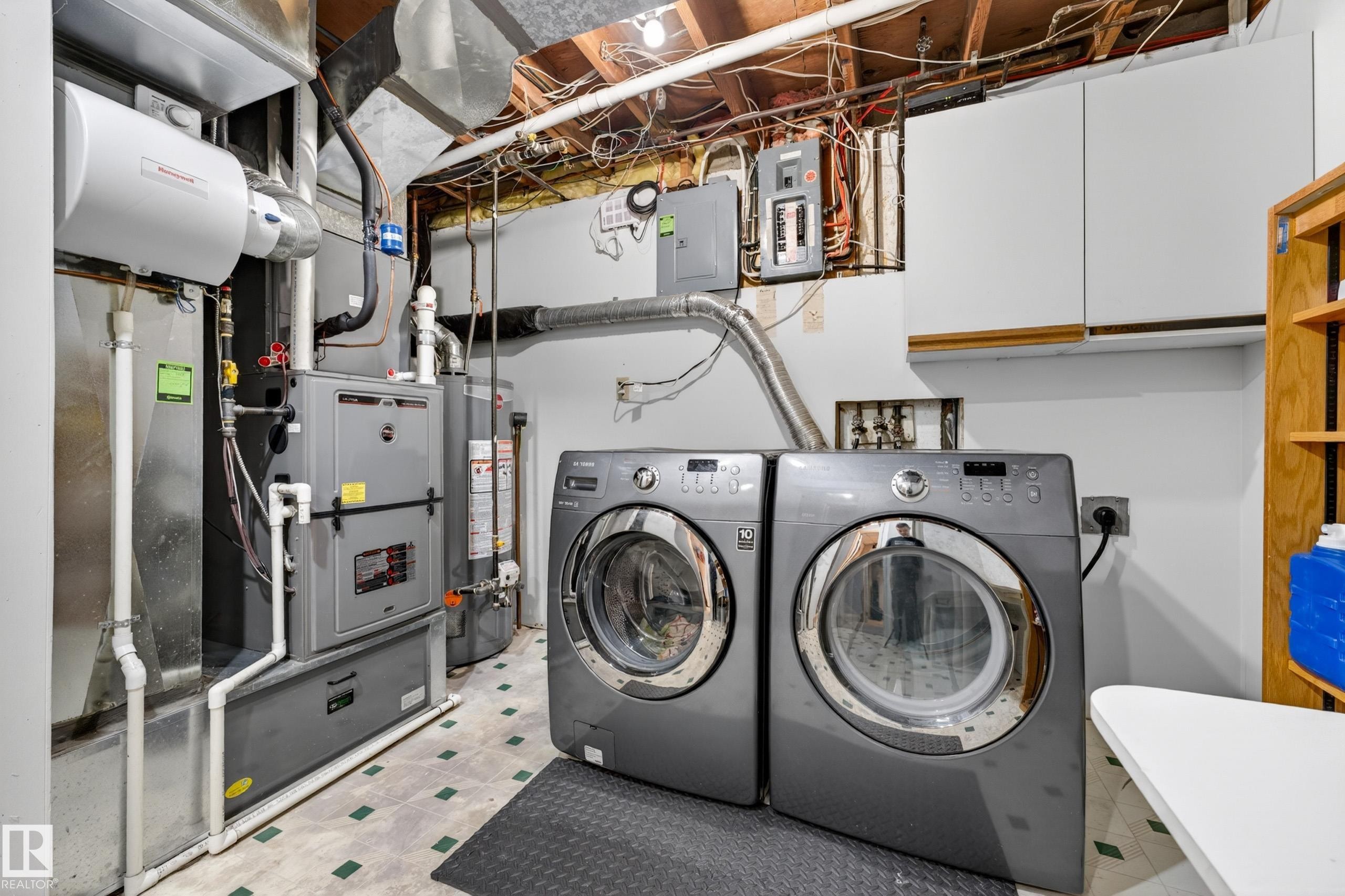 Dedicated laundry area featuring front-loading machines, built-in cabinetry, and utility connections - 5304 90A Avenue, Edmonton, AB - Indoor Photo Showing Laundry Room
