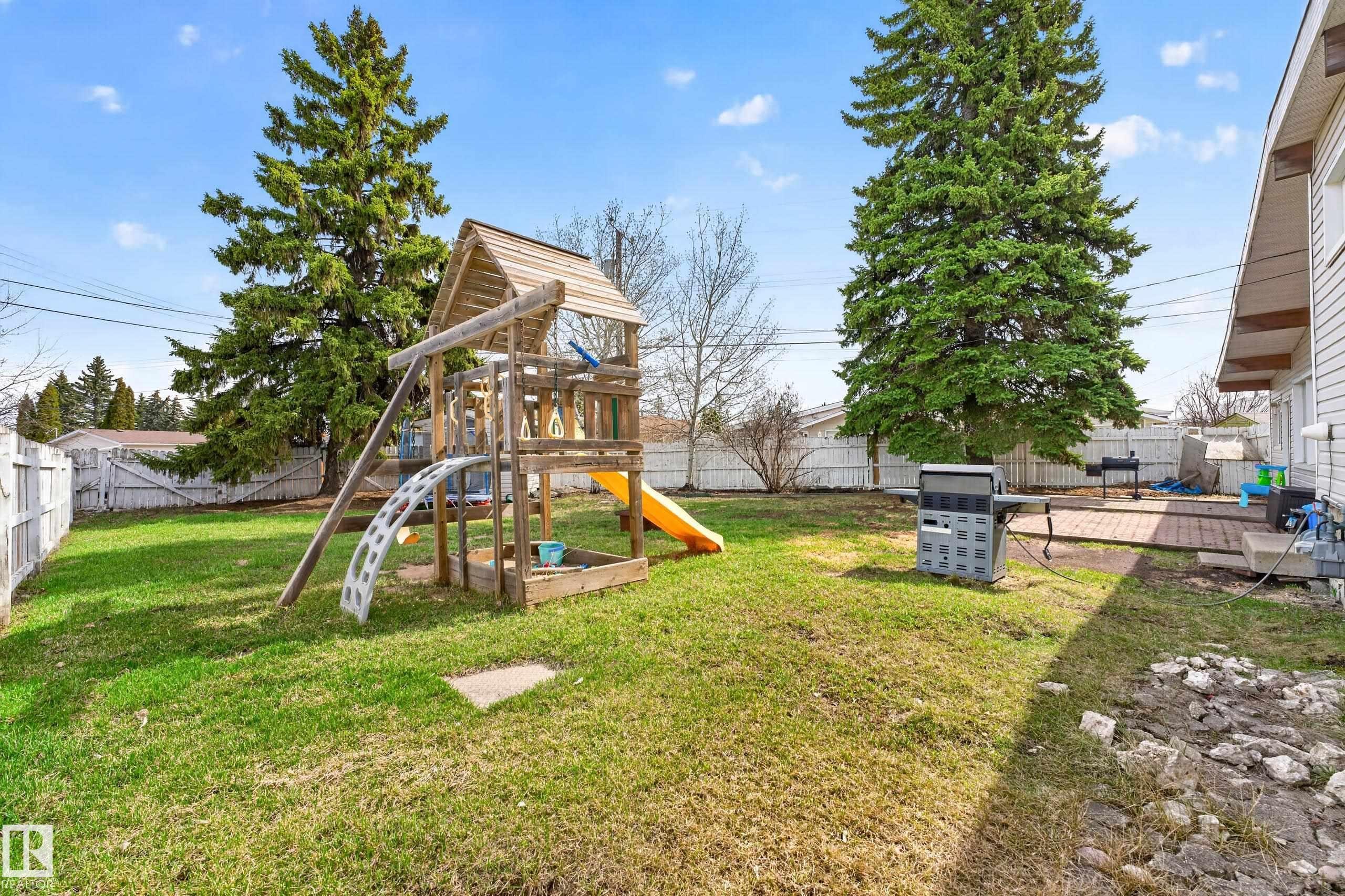 Expansive backyard featuring a lush lawn, privacy fencing, mature trees, and a brick paver patio directly adjacent to the property - 5304 90A Avenue, Edmonton, AB - Outdoor