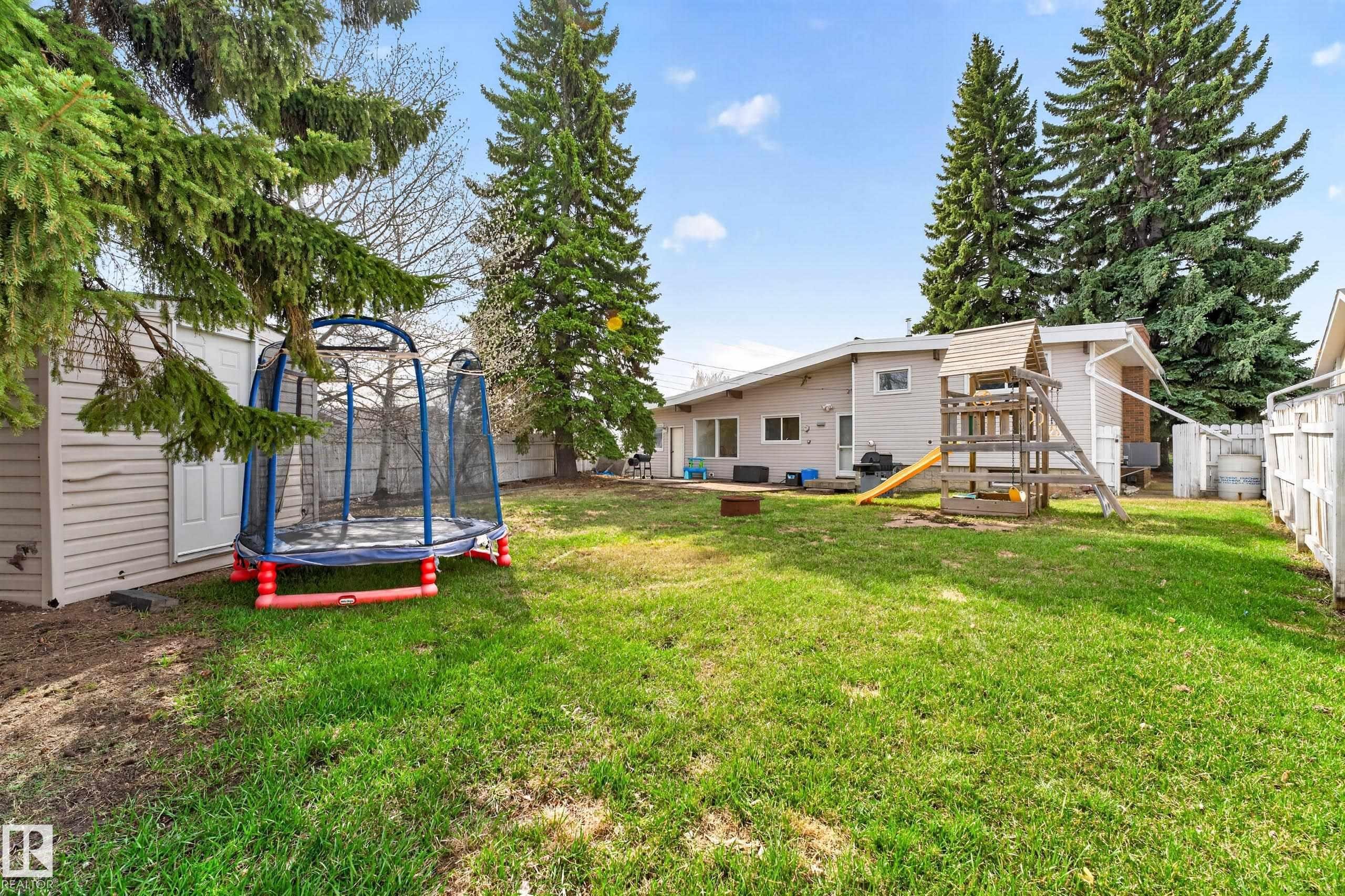 Spacious backyard featuring a manicured lawn, perimeter fencing, and mature evergreen trees - 5304 90A Avenue, Edmonton, AB - Outdoor