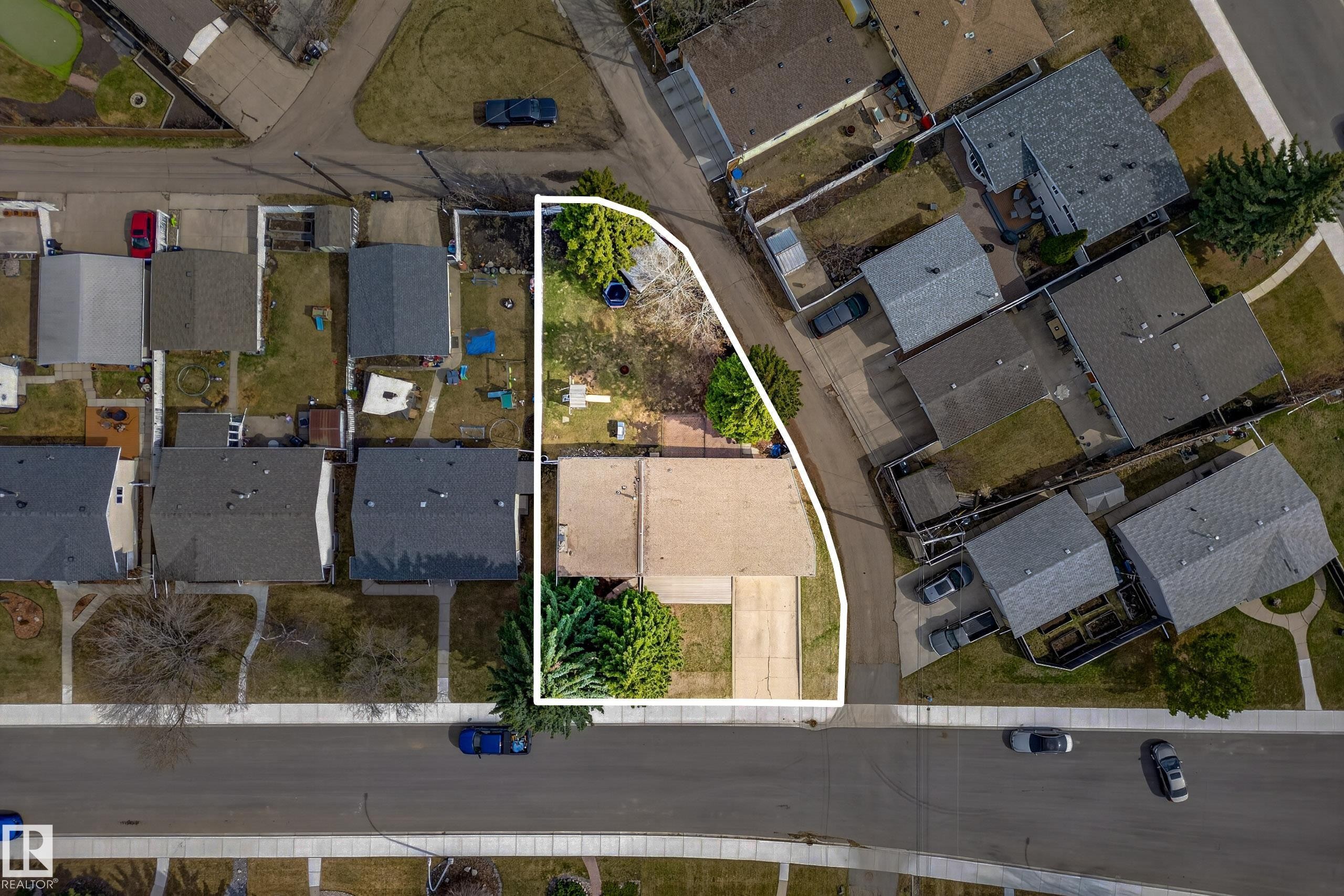 Aerial view of a residential property outlined in white, featuring a paved driveway, front yard with mature trees, and a spacious backyard with established greenery - 5304 90A Avenue, Edmonton, AB -