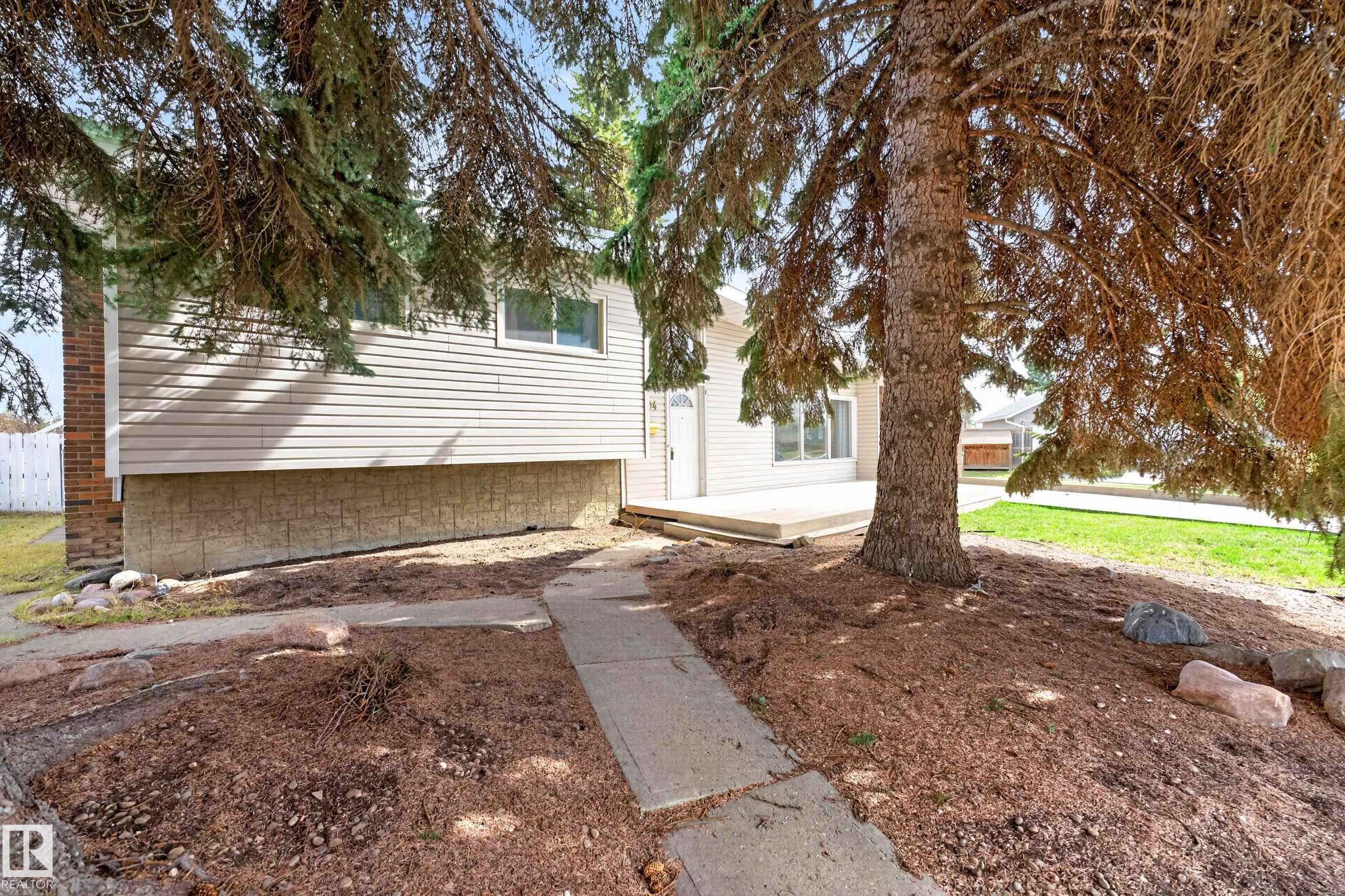 Exterior featuring light-colored siding, a visible foundation, and a concrete pathway - 5304 90A Avenue, Edmonton, AB - Outdoor
