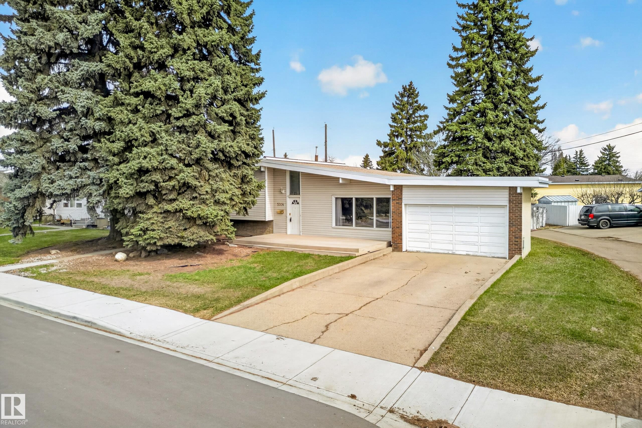 Exterior featuring a single-car garage, partial brick facade, and an asphalt driveway - 5304 90A Avenue, Edmonton, AB - Outdoor