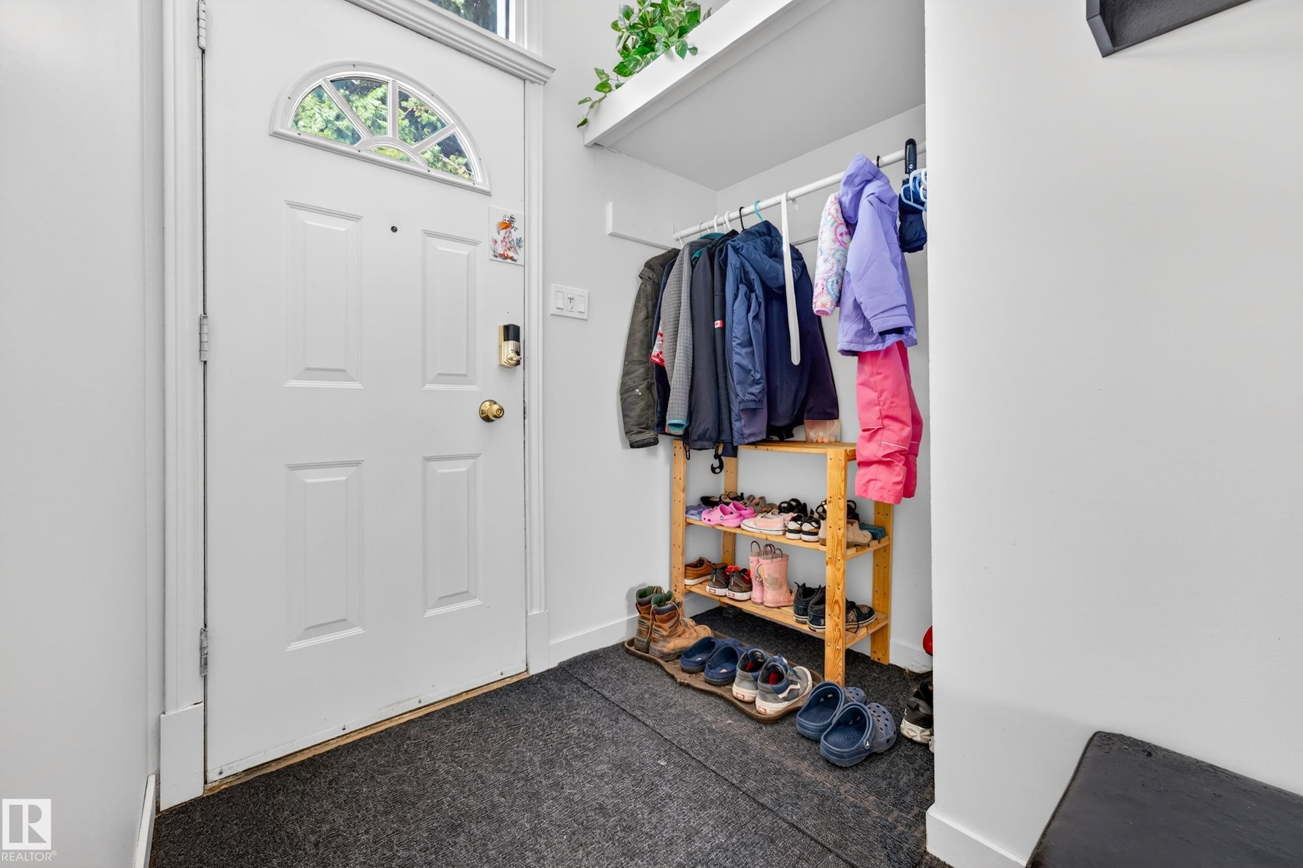 Entryway featuring a paneled door with an arched transom window, a digital smart lock, and an overhead shelf - 5304 90A Avenue, Edmonton, AB - Indoor