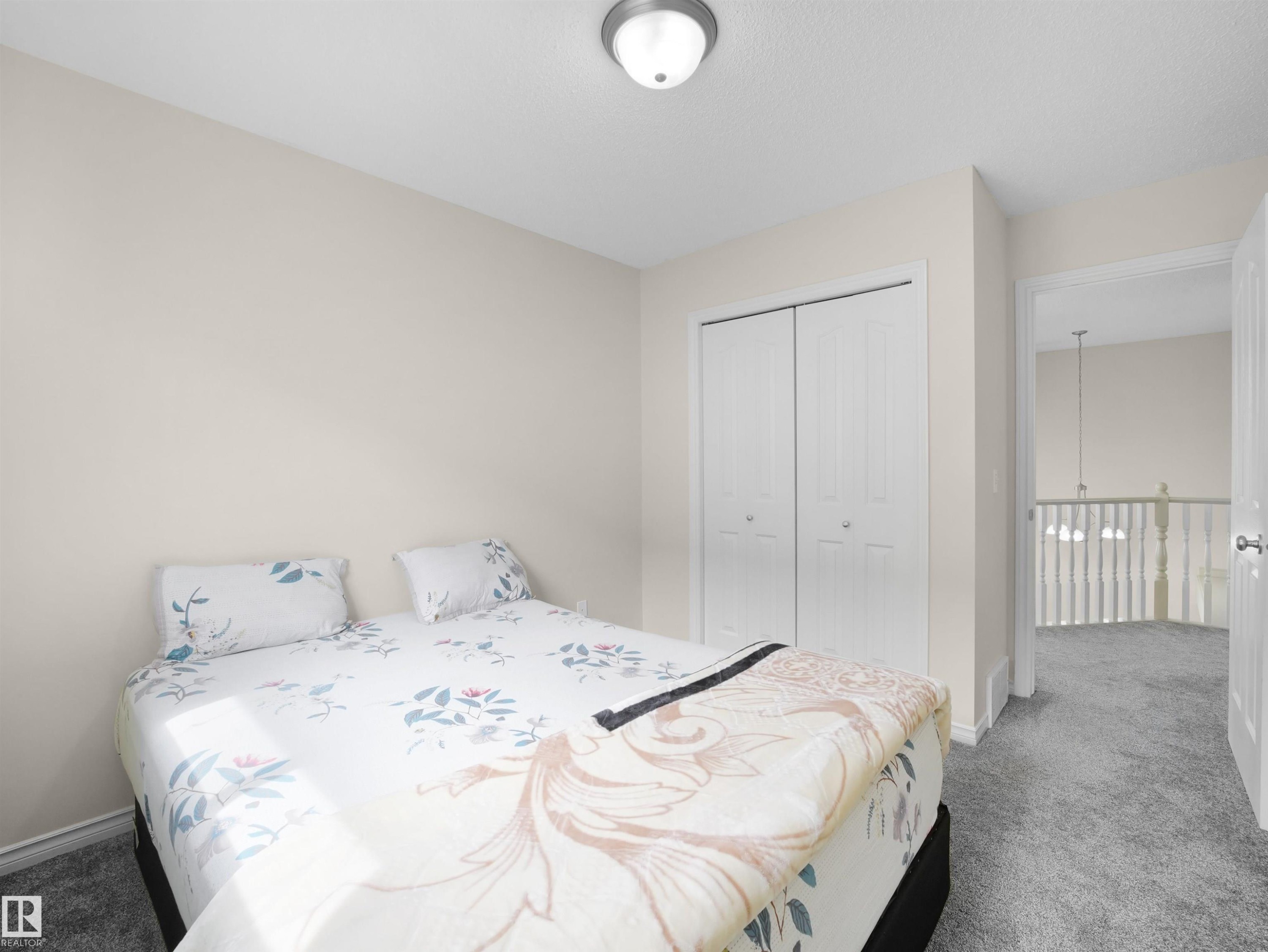 Carpeted room featuring a ceiling-mounted light fixture, bi-fold closet doors, and light-toned wall paint - 7407 Singer Landing, Edmonton, AB - Indoor Photo Showing Bedroom