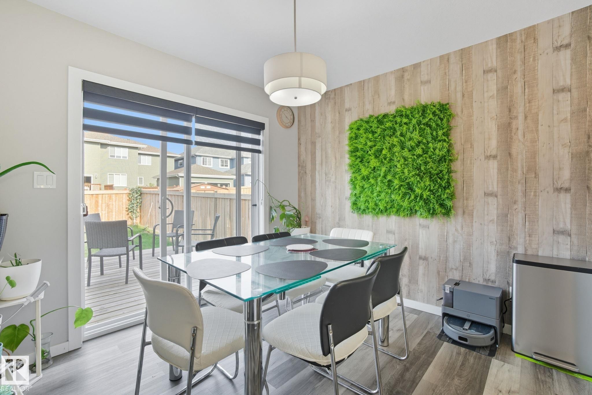 Dining area featuring wood-finish accent wall, ceiling-mounted lighting fixture, and wood-finish flooring - 2039 Wonnacott Way, Edmonton, AB