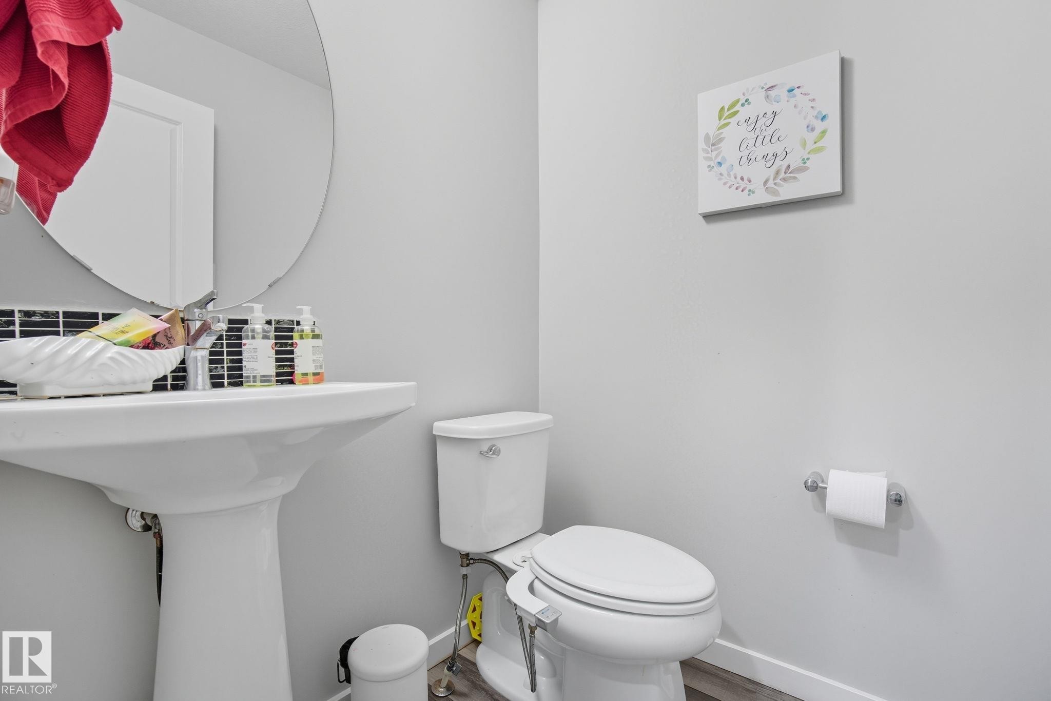 Pedestal sink featuring a chrome faucet and a circular mirror - 2039 Wonnacott Way, Edmonton, AB
