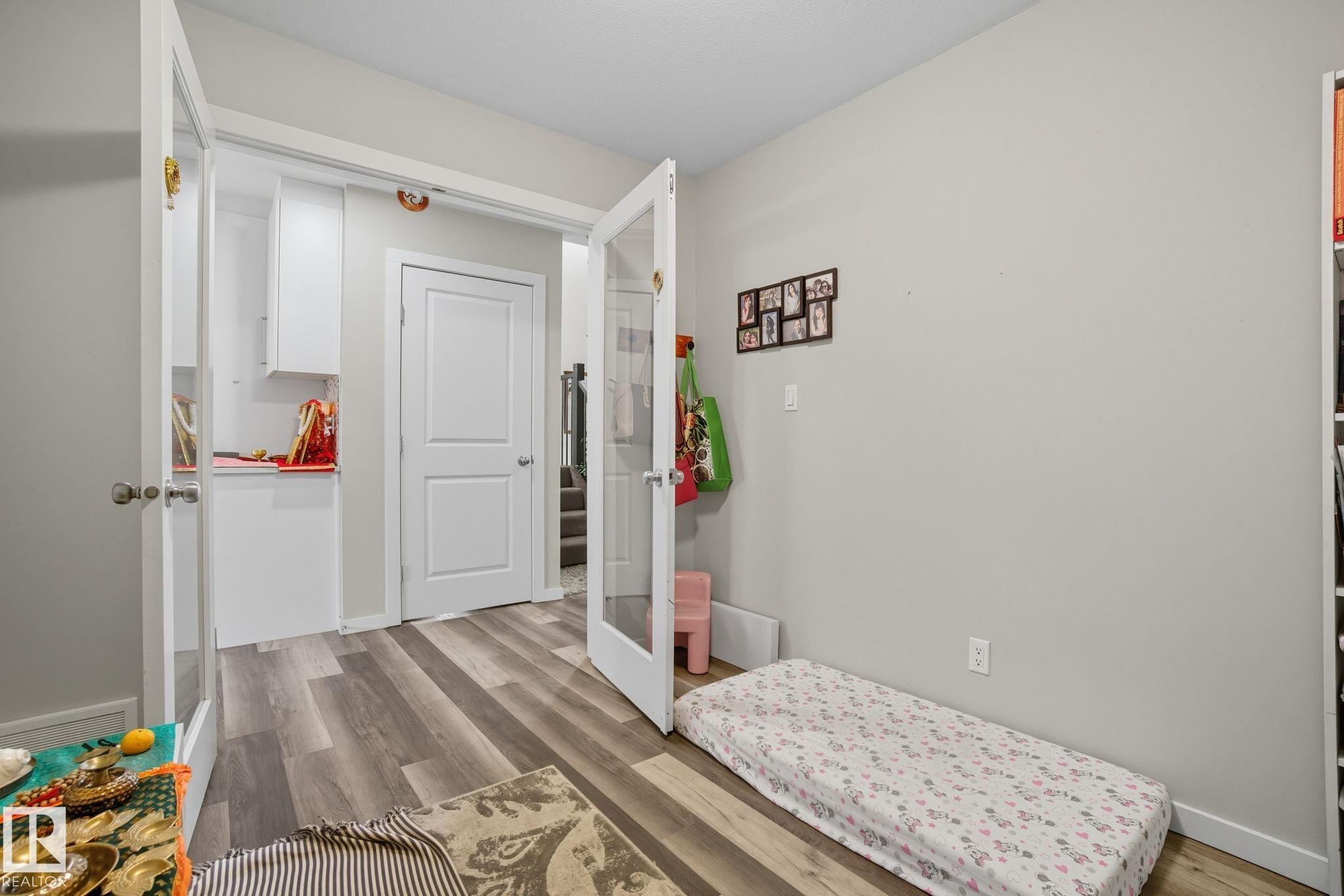 Room featuring wood-finish flooring, light grey wall paint, and white trim - 2039 Wonnacott Way, Edmonton, AB