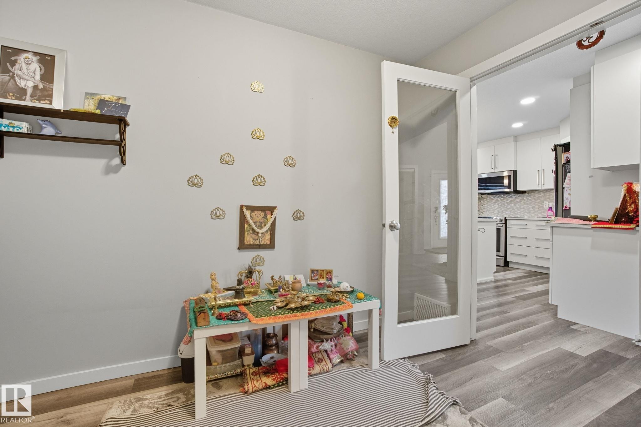 Glass-paneled interior door providing access to a kitchen featuring white cabinetry, stainless steel appliances, and a tiled backsplash - 2039 Wonnacott Way, Edmonton, AB