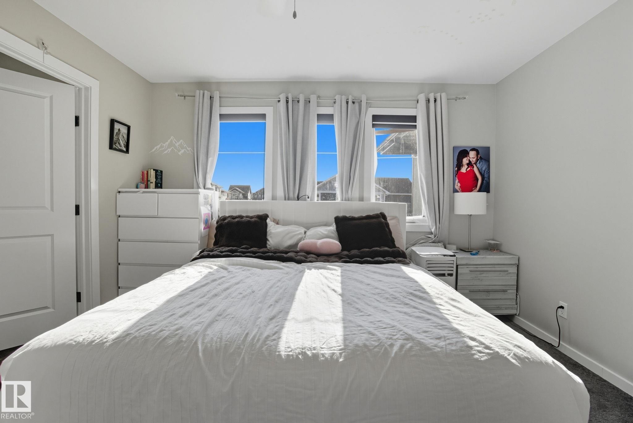 Bedroom featuring light gray walls, dark carpet flooring, and a white paneled door - 2039 Wonnacott Way, Edmonton, AB