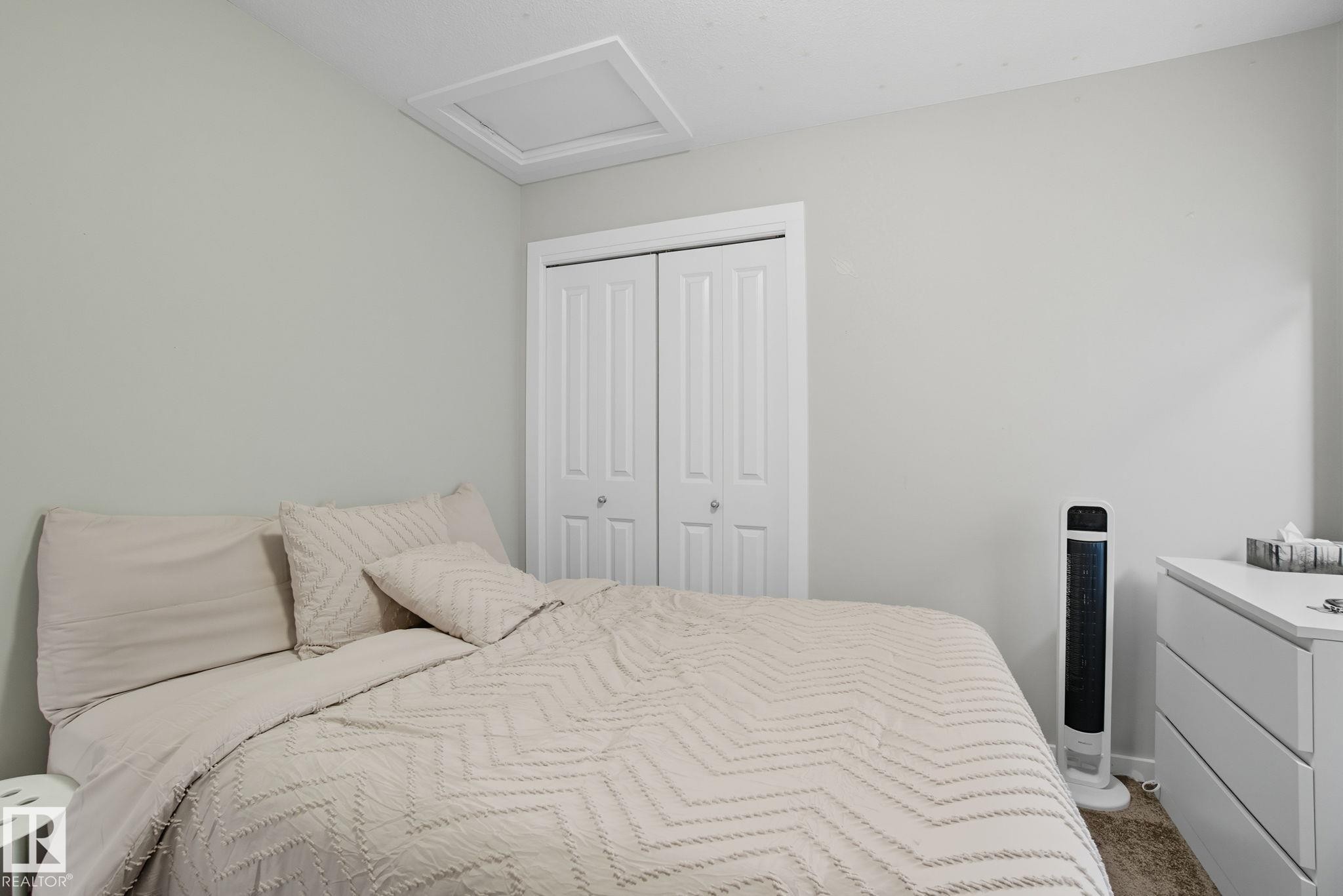 Bedroom featuring neutral wall paint, white bi-fold closet doors, and light-colored carpeting - 2039 Wonnacott Way, Edmonton, AB
