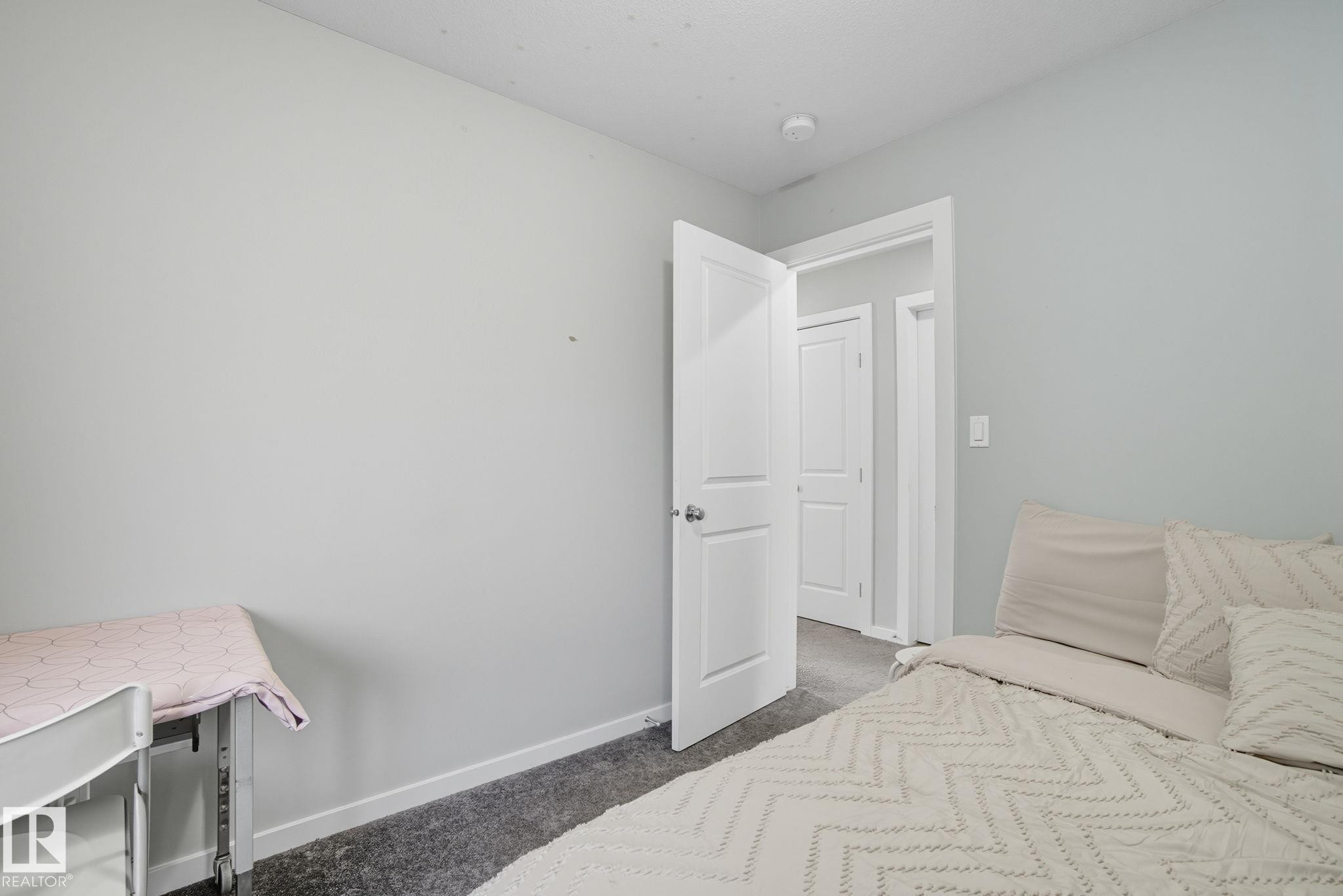 Interior room featuring light gray wall paint, white trim, and dark gray carpeting - 2039 Wonnacott Way, Edmonton, AB