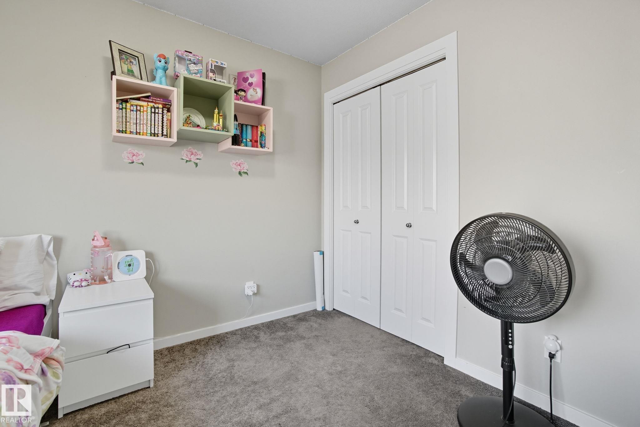Neutral tone wall color with white baseboards, gray carpeted flooring, and a white bi-fold closet door - 2039 Wonnacott Way, Edmonton, AB