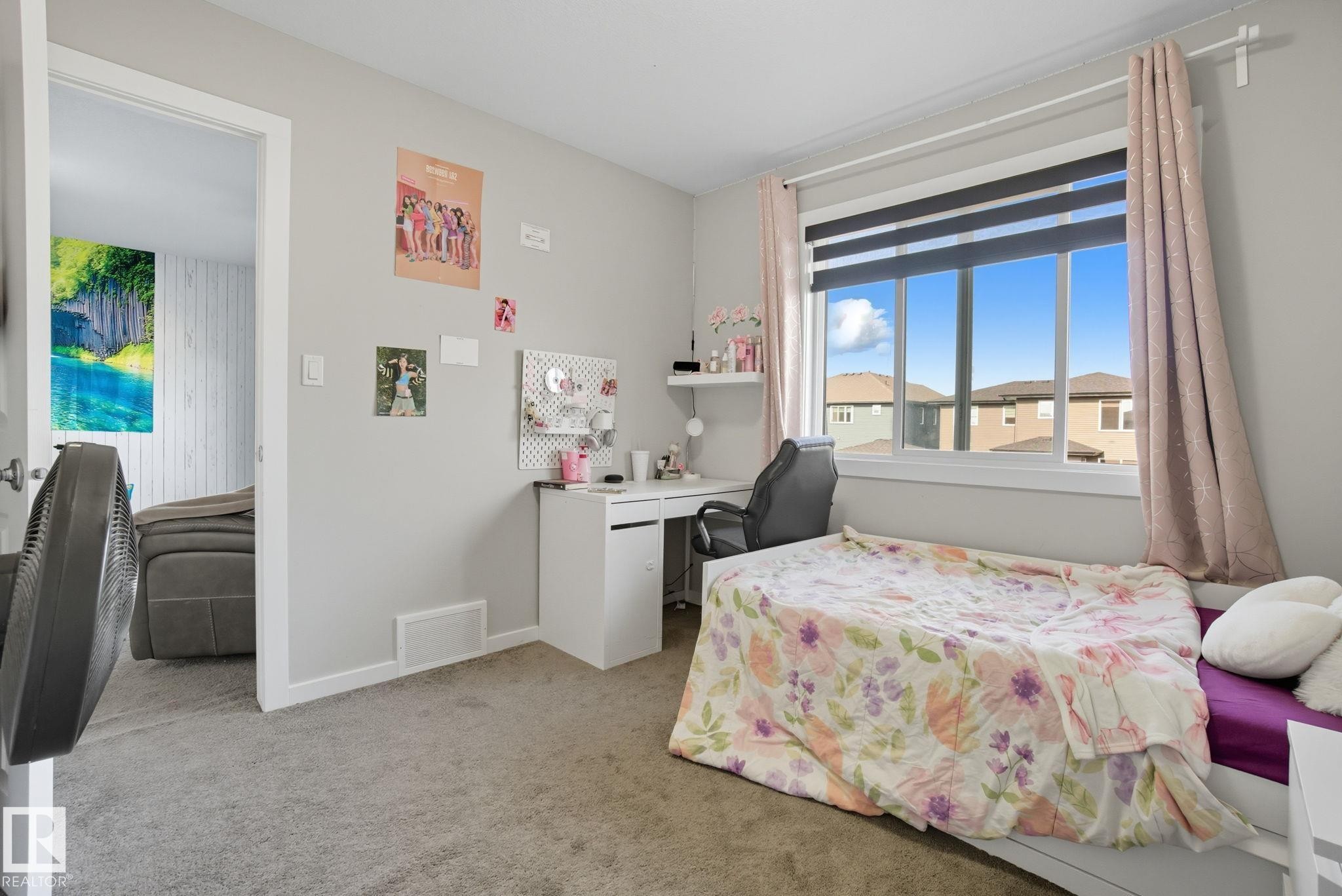 Room featuring a large window with dual-layer blinds and drapes, light gray walls, and gray carpeting - 2039 Wonnacott Way, Edmonton, AB