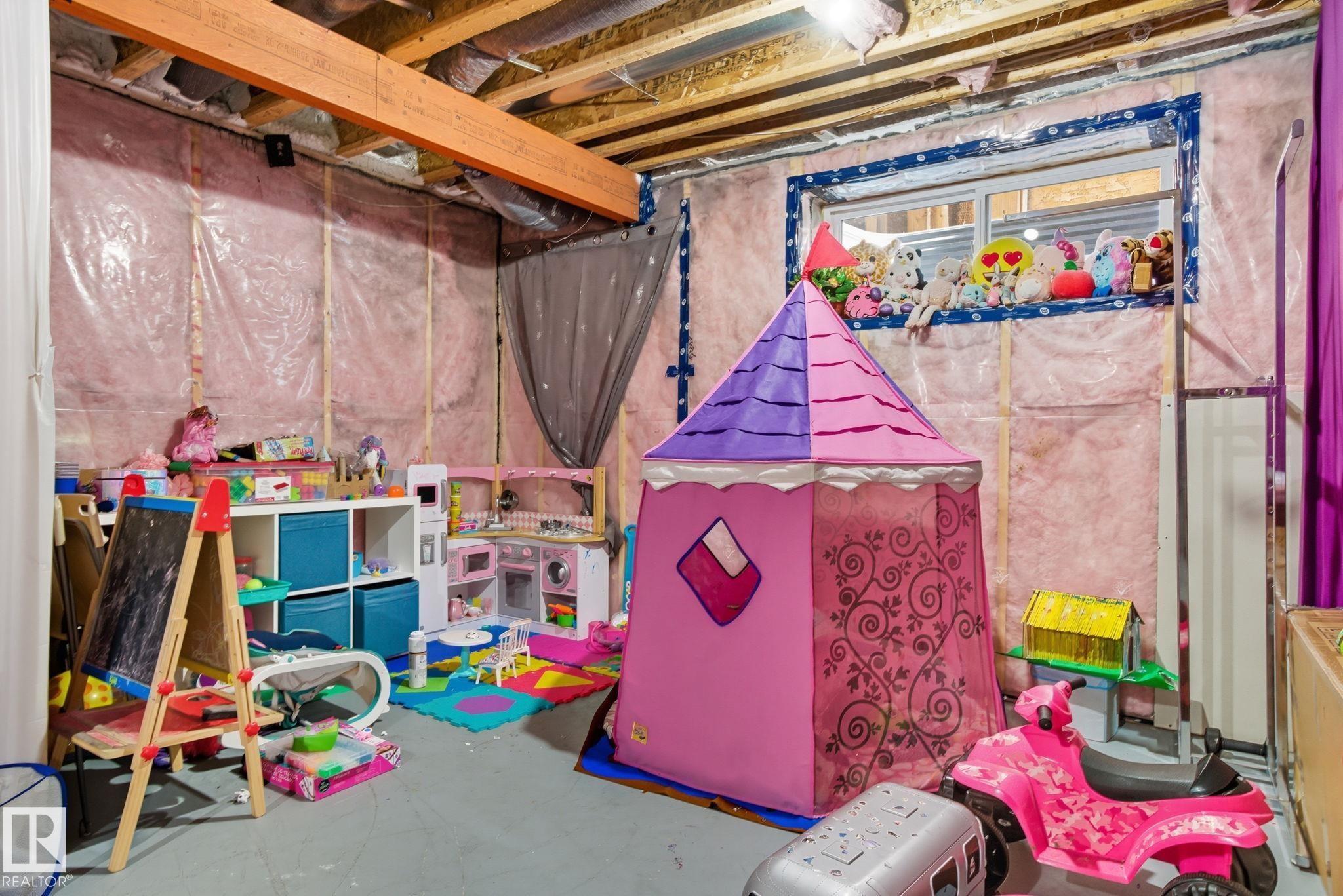 Unfinished basement space featuring exposed ceiling joists and wall insulation, a visible window, and a concrete floor - 2039 Wonnacott Way, Edmonton, AB