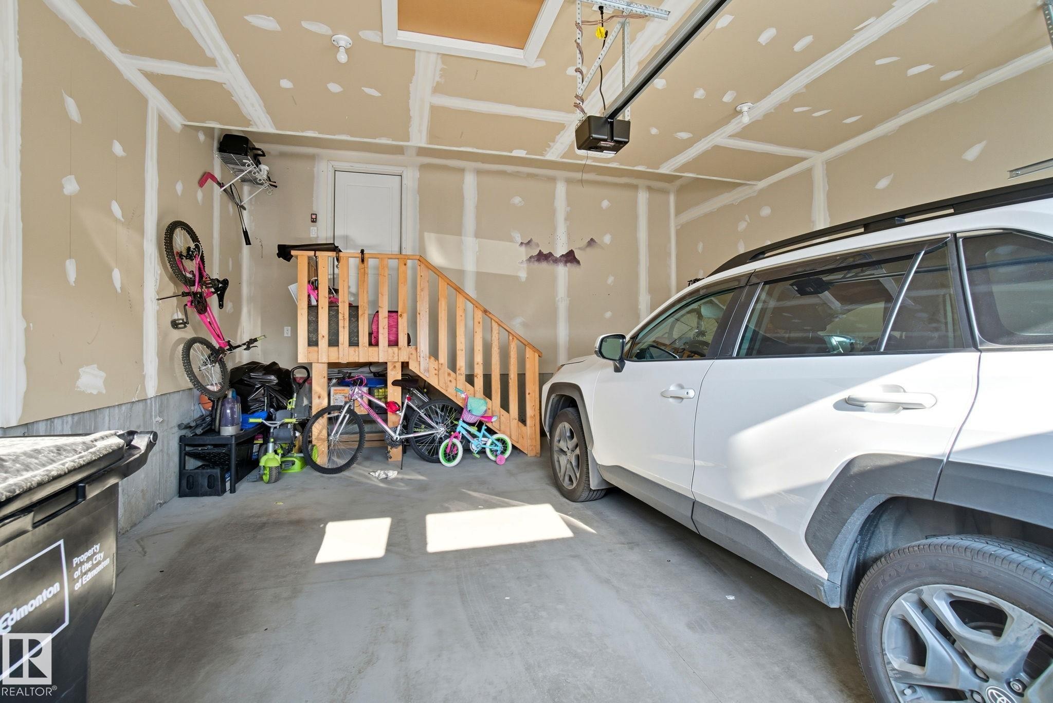 Attached garage featuring a concrete floor and an overhead garage door opener - 2039 Wonnacott Way, Edmonton, AB