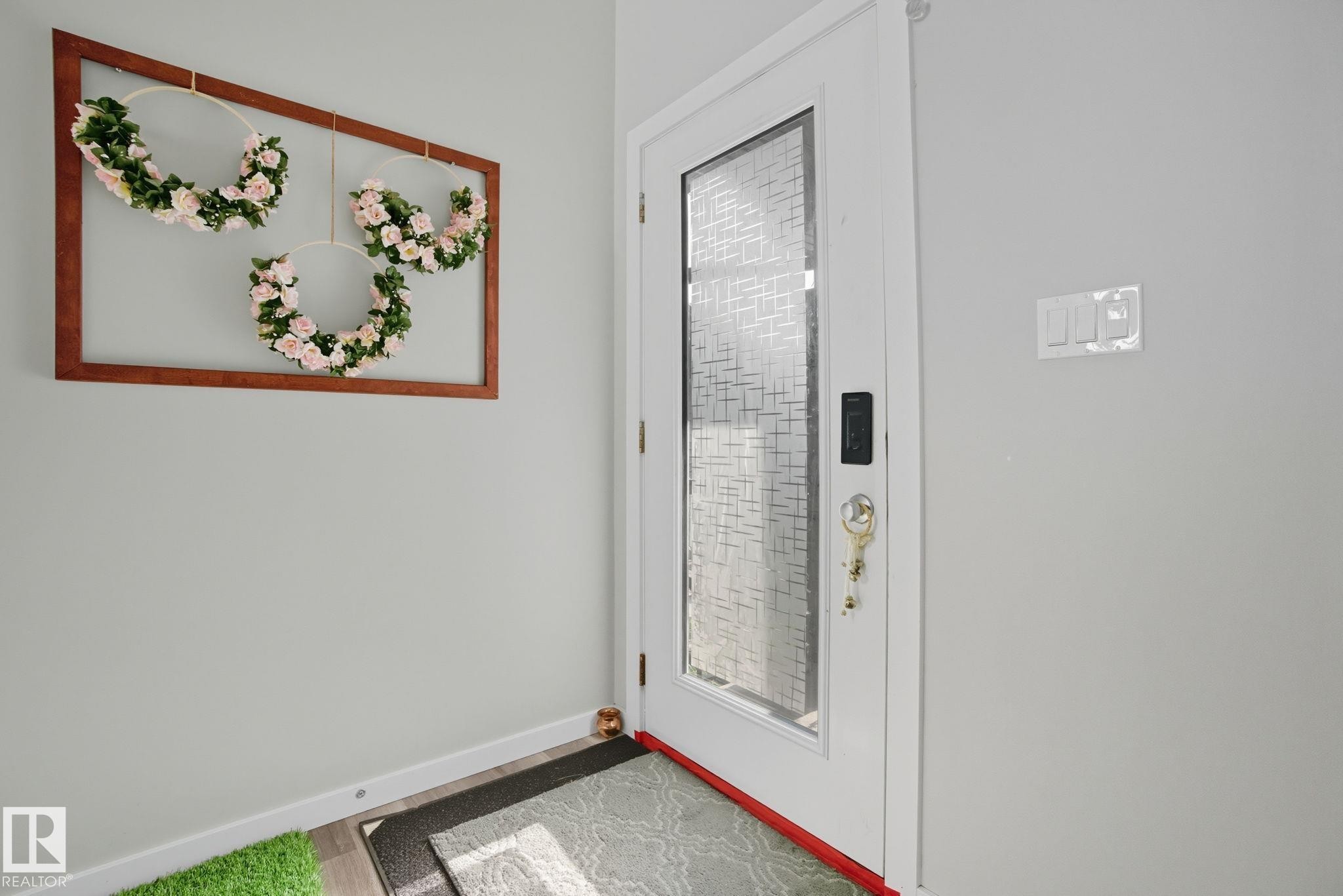 Entry door with frosted privacy glass panel, white trim, and a smart lock system - 2039 Wonnacott Way, Edmonton, AB