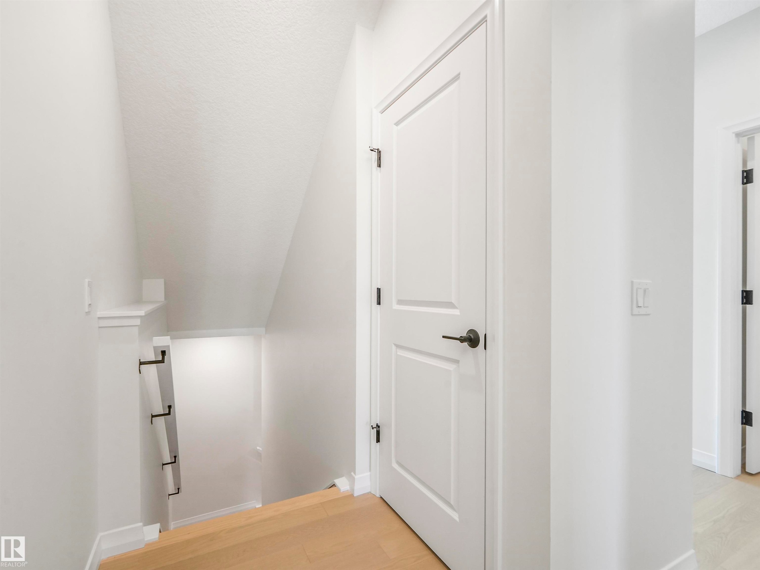 The property features light wood flooring, white painted walls, and white doors with dark hardware - 19 Nettle Crescent, St. Albert, AB - Indoor Photo Showing Other Room