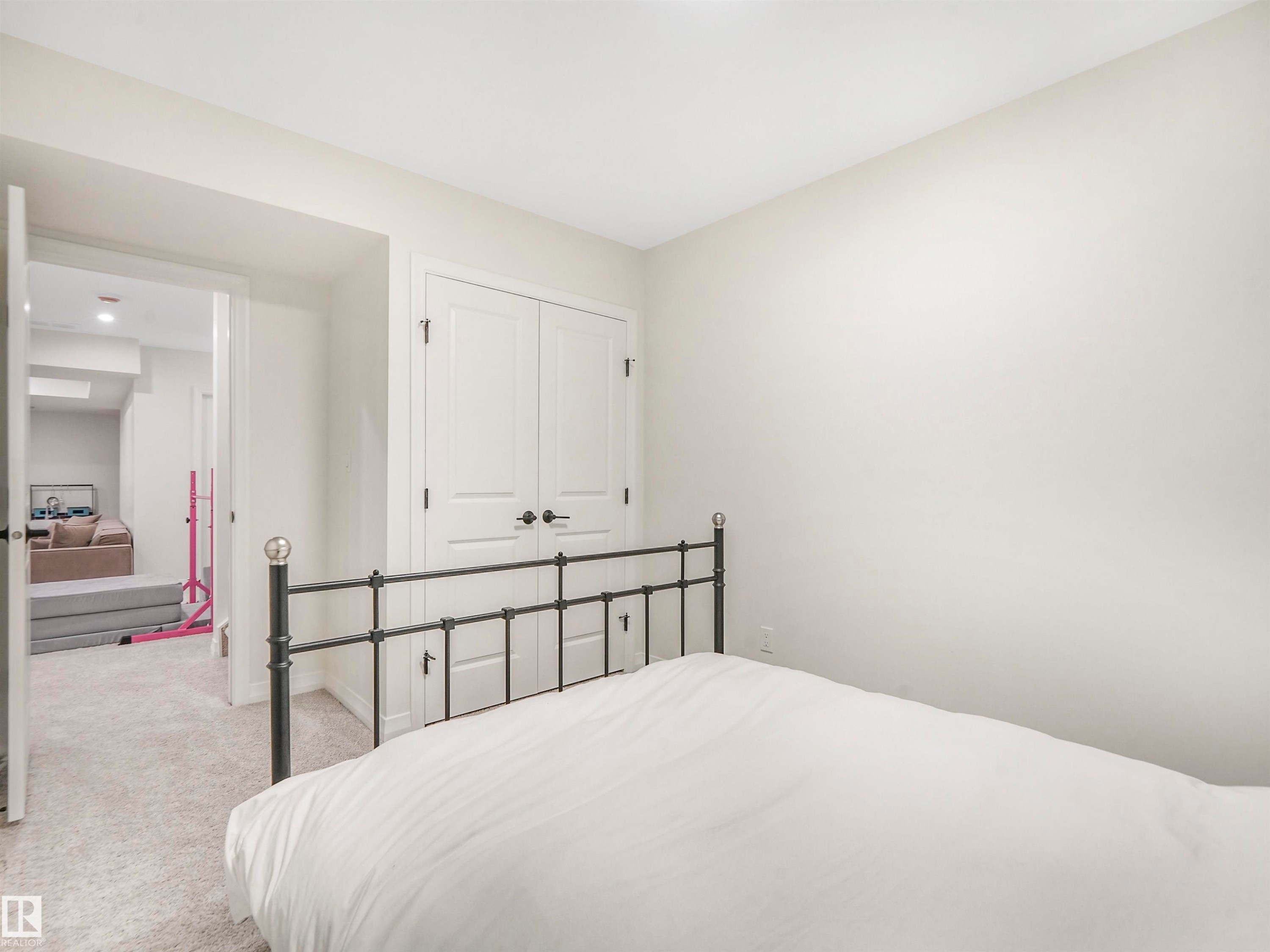 This room features light-colored carpeting and a set of white double doors with black hardware - 19 Nettle Crescent, St. Albert, AB - Indoor Photo Showing Bedroom