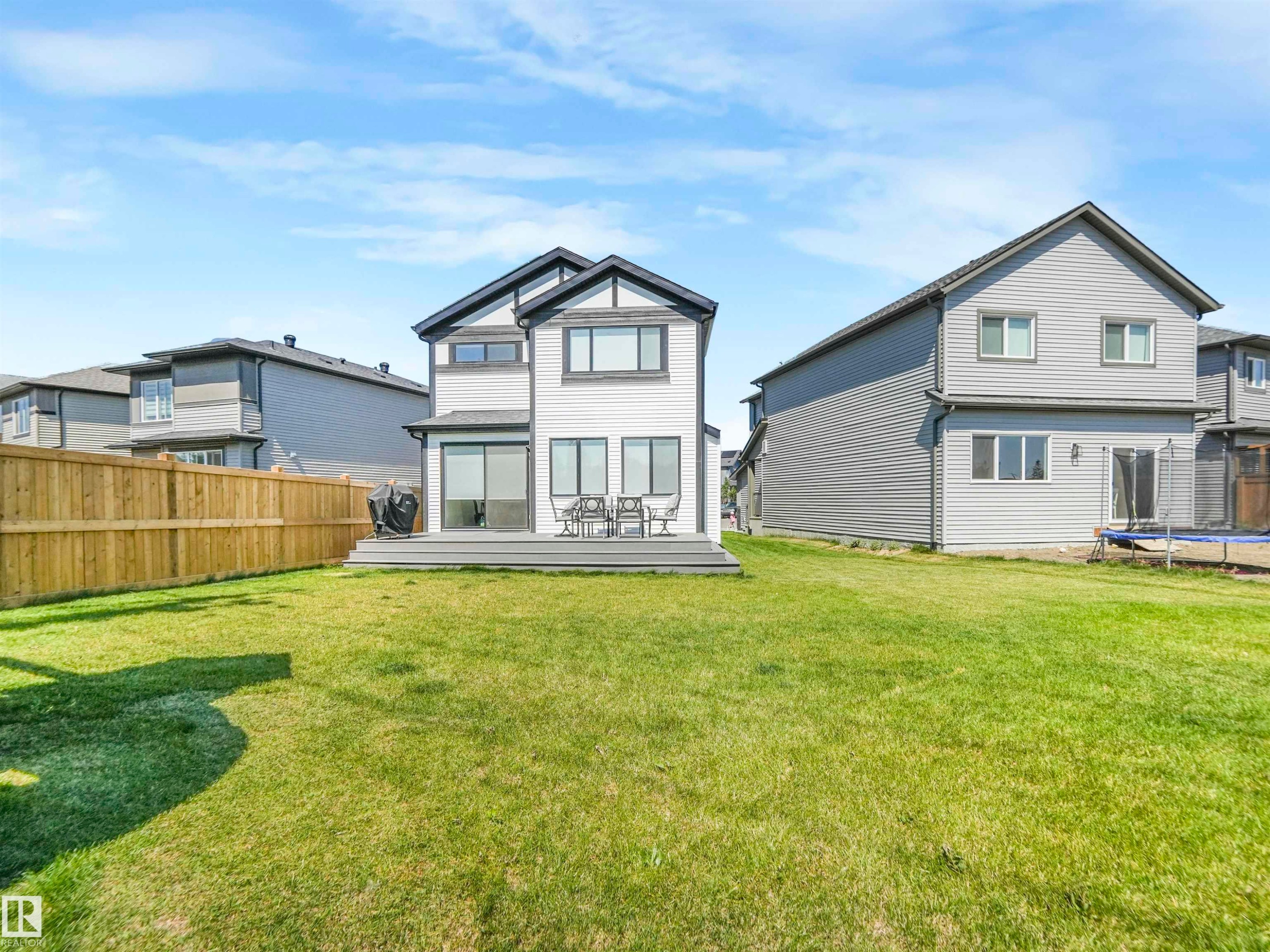 The property features a spacious backyard with a large lawn area and a wooden privacy fence - 19 Nettle Crescent, St. Albert, AB - Outdoor