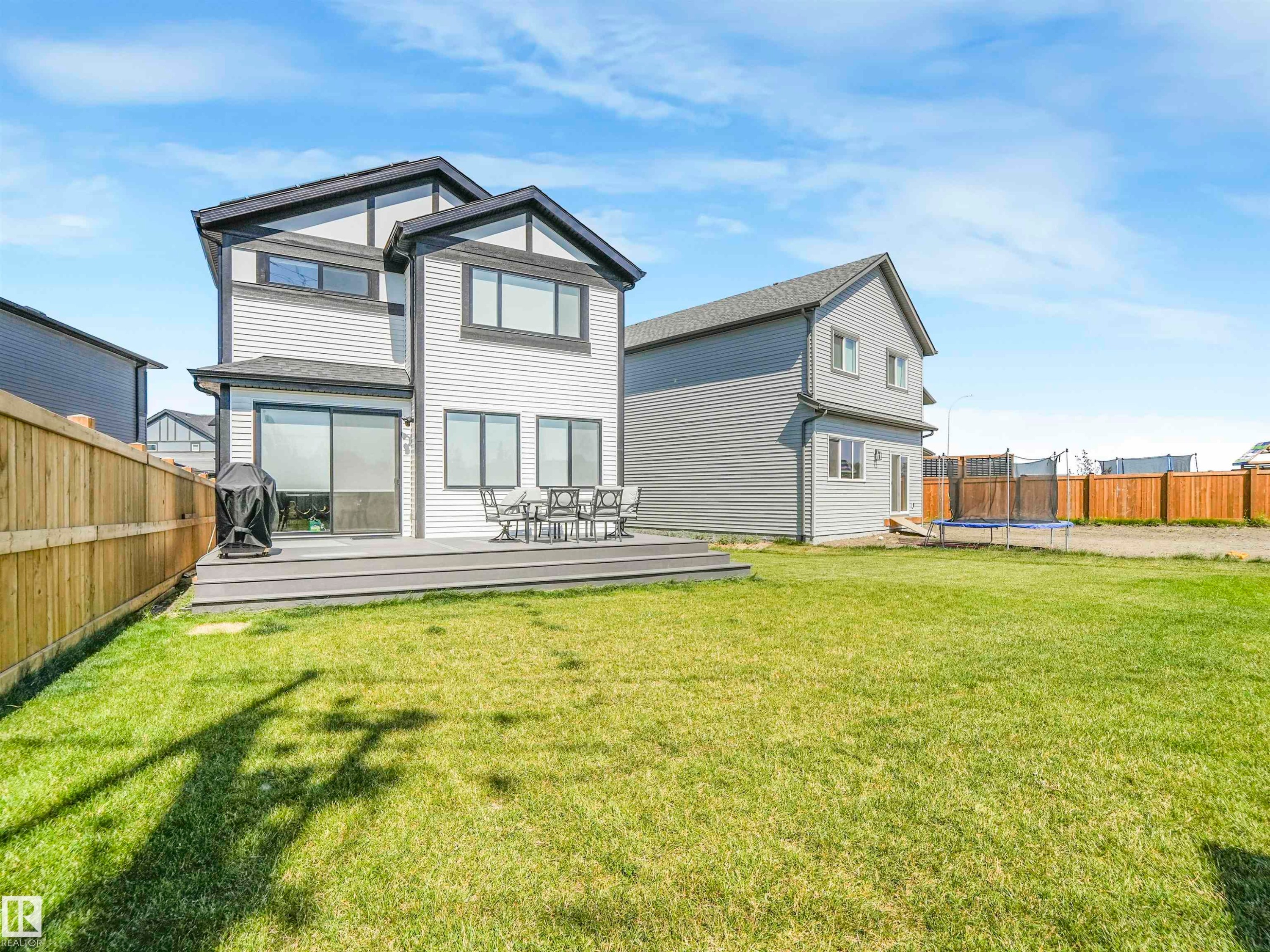 The property features a spacious backyard with a well-maintained lawn and a wooden fence - 19 Nettle Crescent, St. Albert, AB - Outdoor