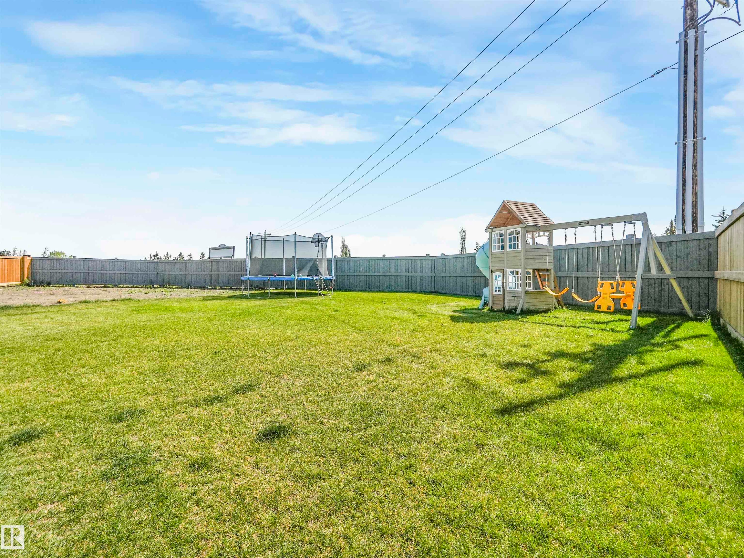 The property features an expansive green lawn, enclosed by a tall wooden fence - 19 Nettle Crescent, St. Albert, AB - Outdoor