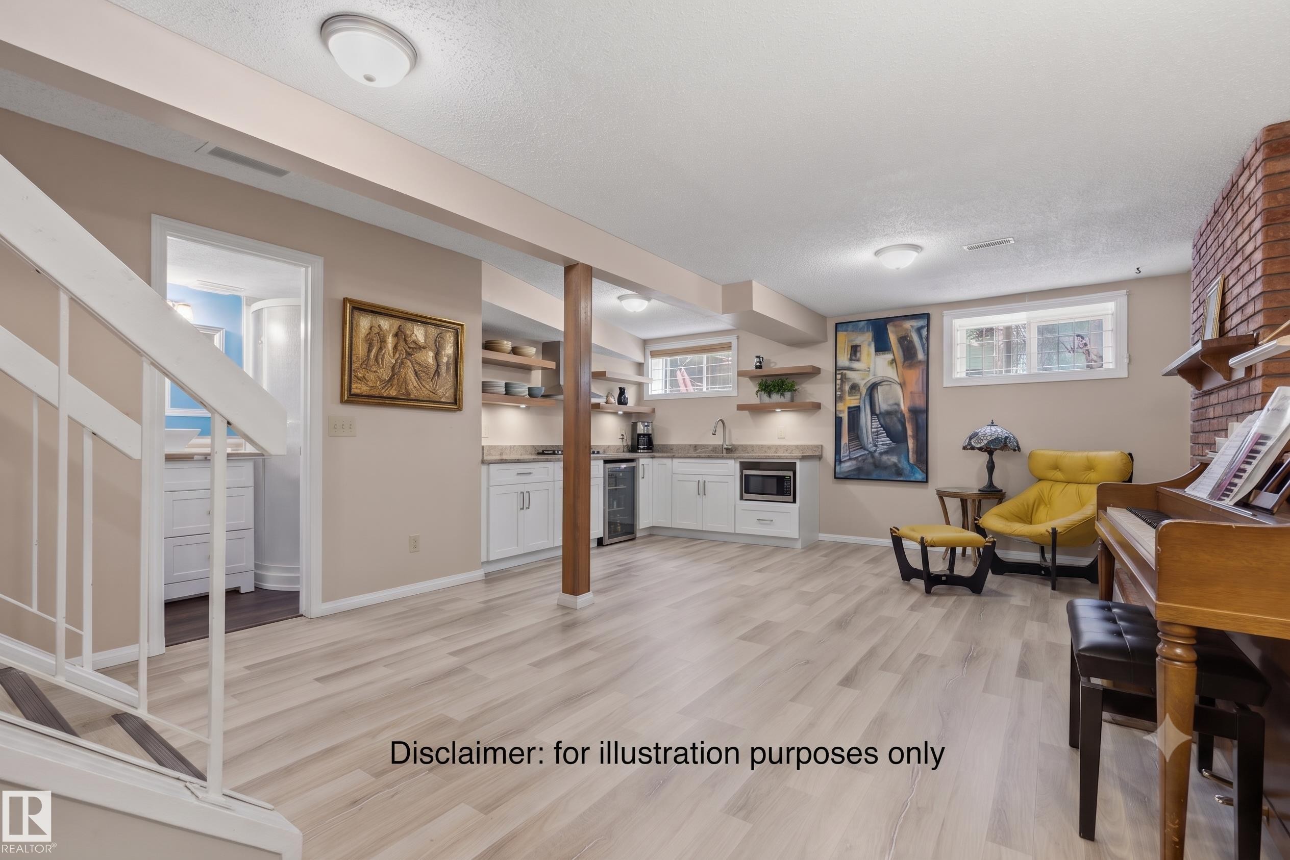 Expansive lower-level space featuring wood-finish flooring, a wet bar with white cabinetry and light-toned countertops, and a brick-finish accent wall - 7422 188 Street, Edmonton, AB