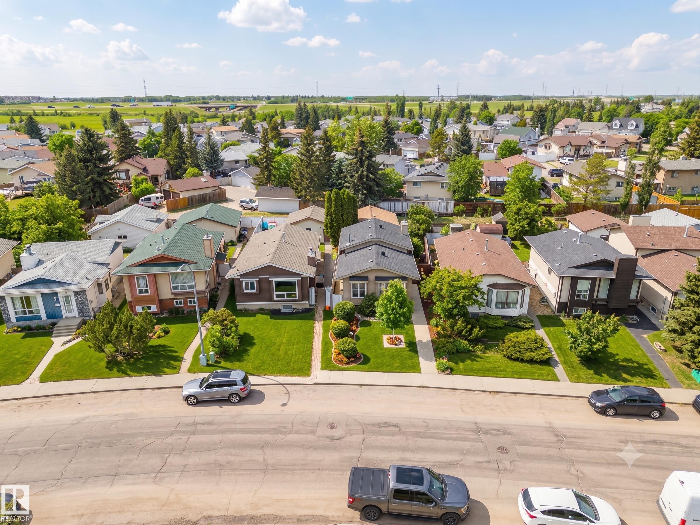 Residential neighborhood featuring a variety of architectural styles, mature trees, manicured lawns, and concrete sidewalks - 7422 188 Street, Edmonton, AB