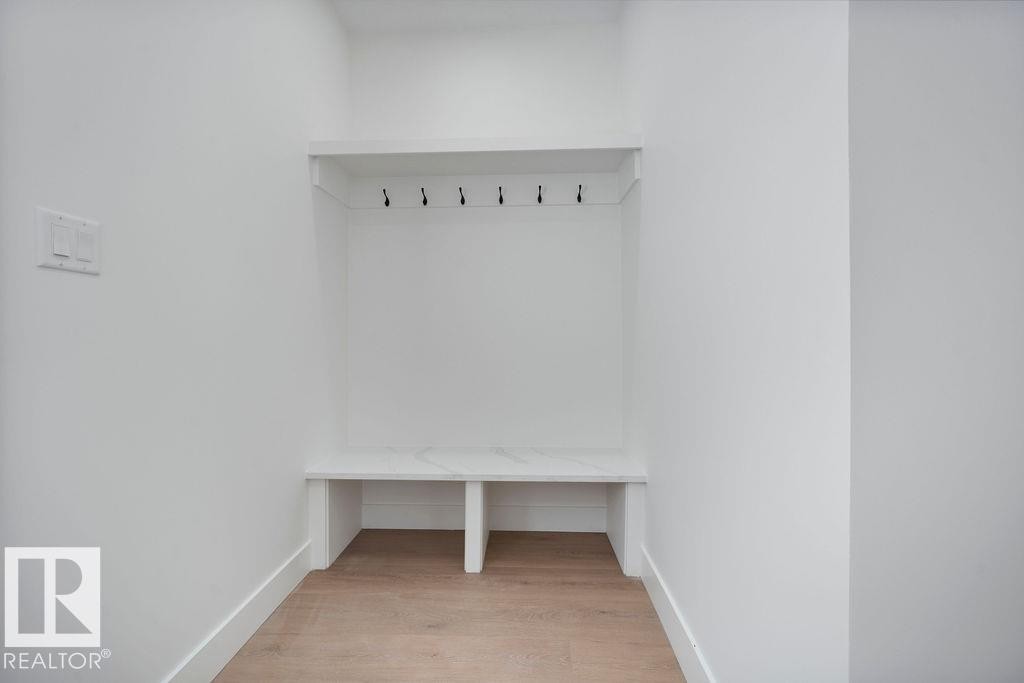 Entryway with light hardwood floors, a built-in bench, and coat hooks - 12307 91 St Nw, Edmonton, AB - Indoor