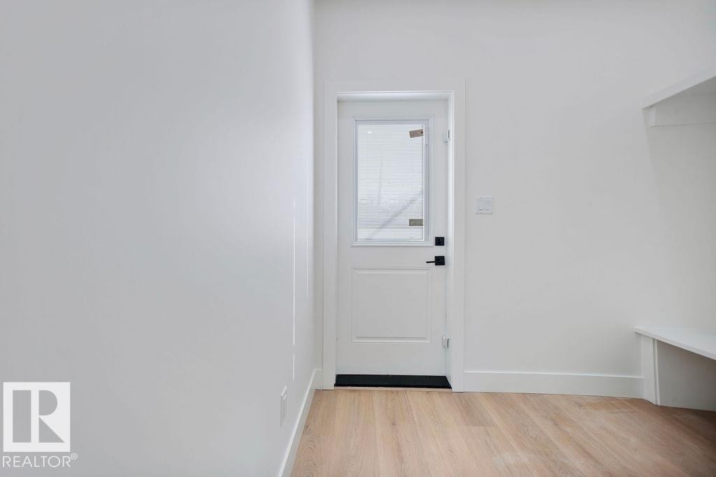 Entryway featuring light hardwood floors, white walls, and a white door with a window and black hardware - 12307 91 St Nw, Edmonton, AB - Indoor Photo Showing Other Room