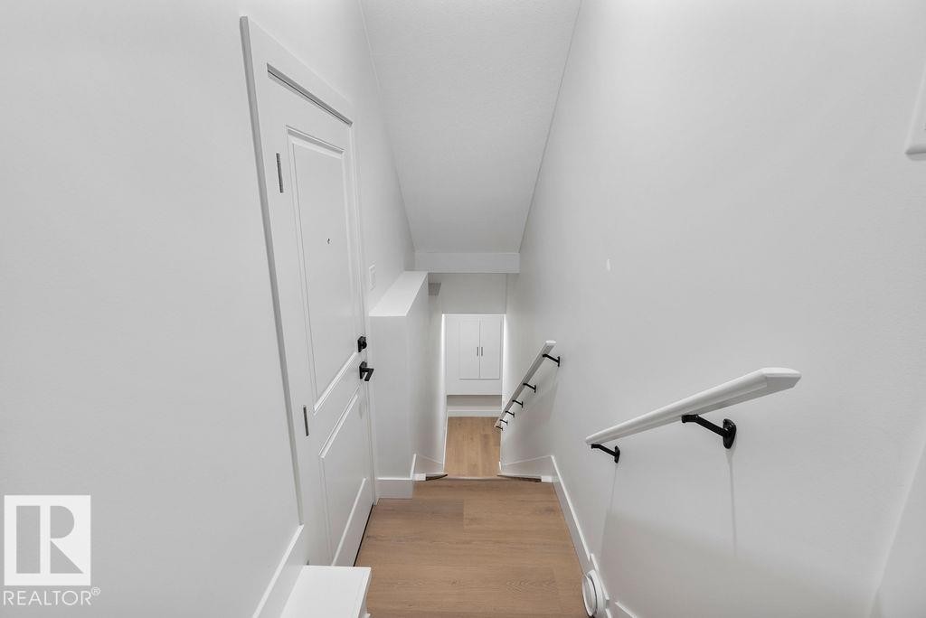 The property features a bright hallway with white walls and light wood flooring, leading to a white door with black hardware - 12307 91 St Nw, Edmonton, AB - Indoor Photo Showing Other Room