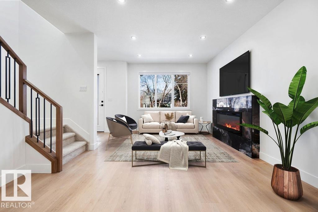 Living area featuring light wood flooring, an electric fireplace with a dark stone surround, and recessed lighting - 12307 91 St Nw, Edmonton, AB - Indoor Photo Showing Living Room