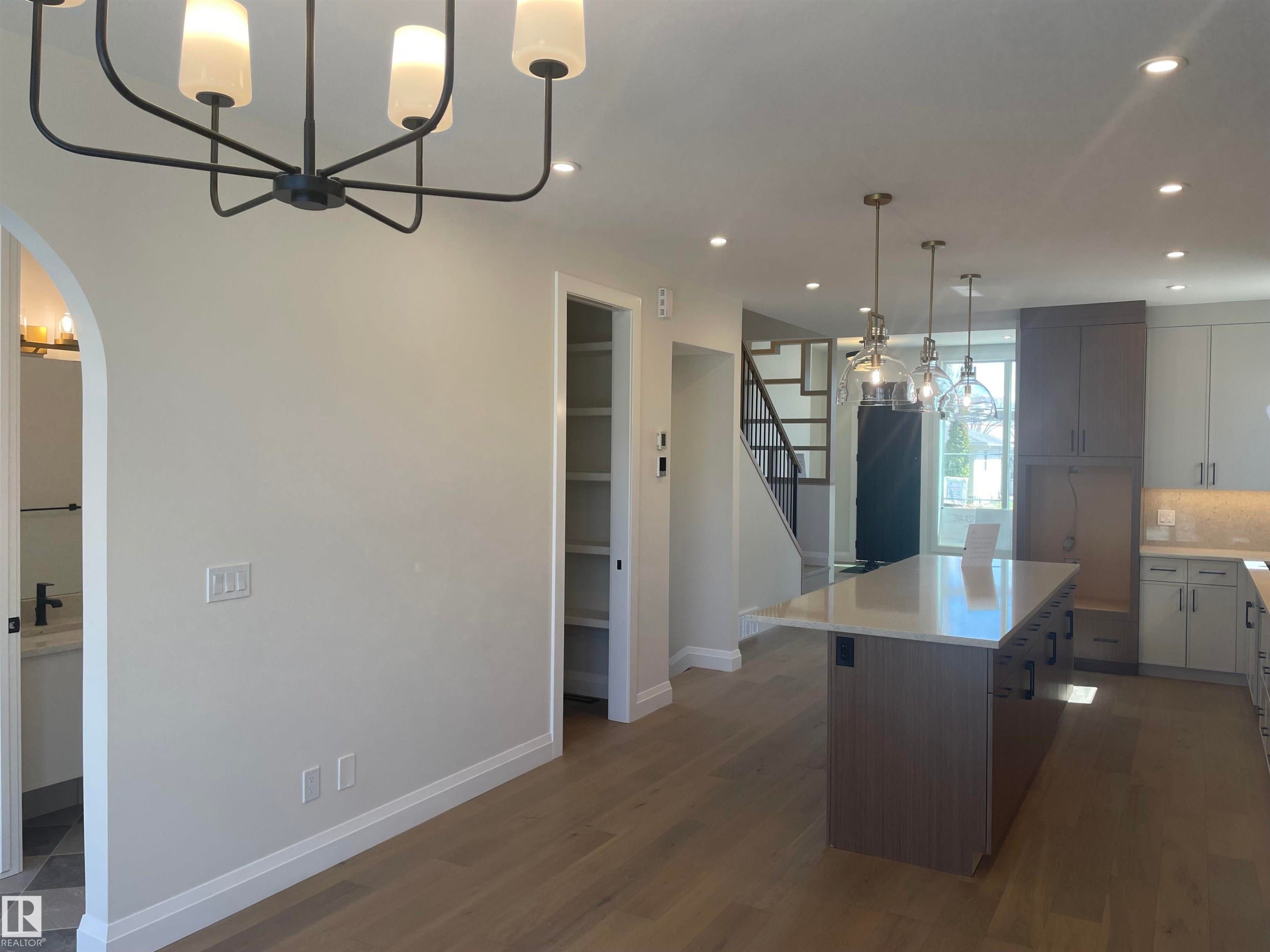 Modern kitchen featuring a large island with a quartz countertop, pendant lighting, and recessed lighting throughout - 14344 92A Avenue, Edmonton, AB - Indoor Photo Showing Kitchen