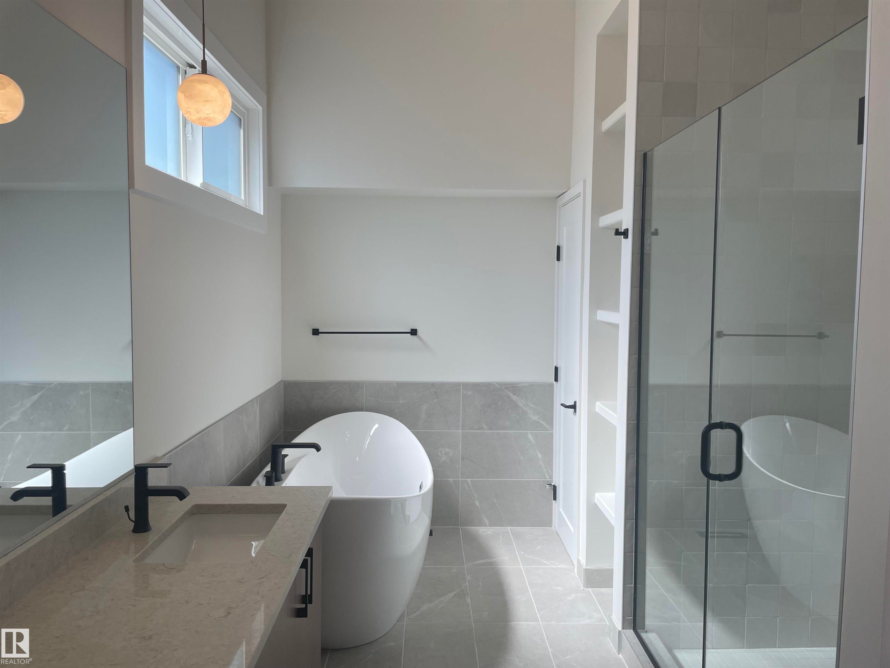 Modern bathroom featuring a freestanding tub, glass-enclosed shower, a double vanity with integrated sinks, and matte black fixtures - 14344 92A Avenue, Edmonton, AB - Indoor Photo Showing Bathroom