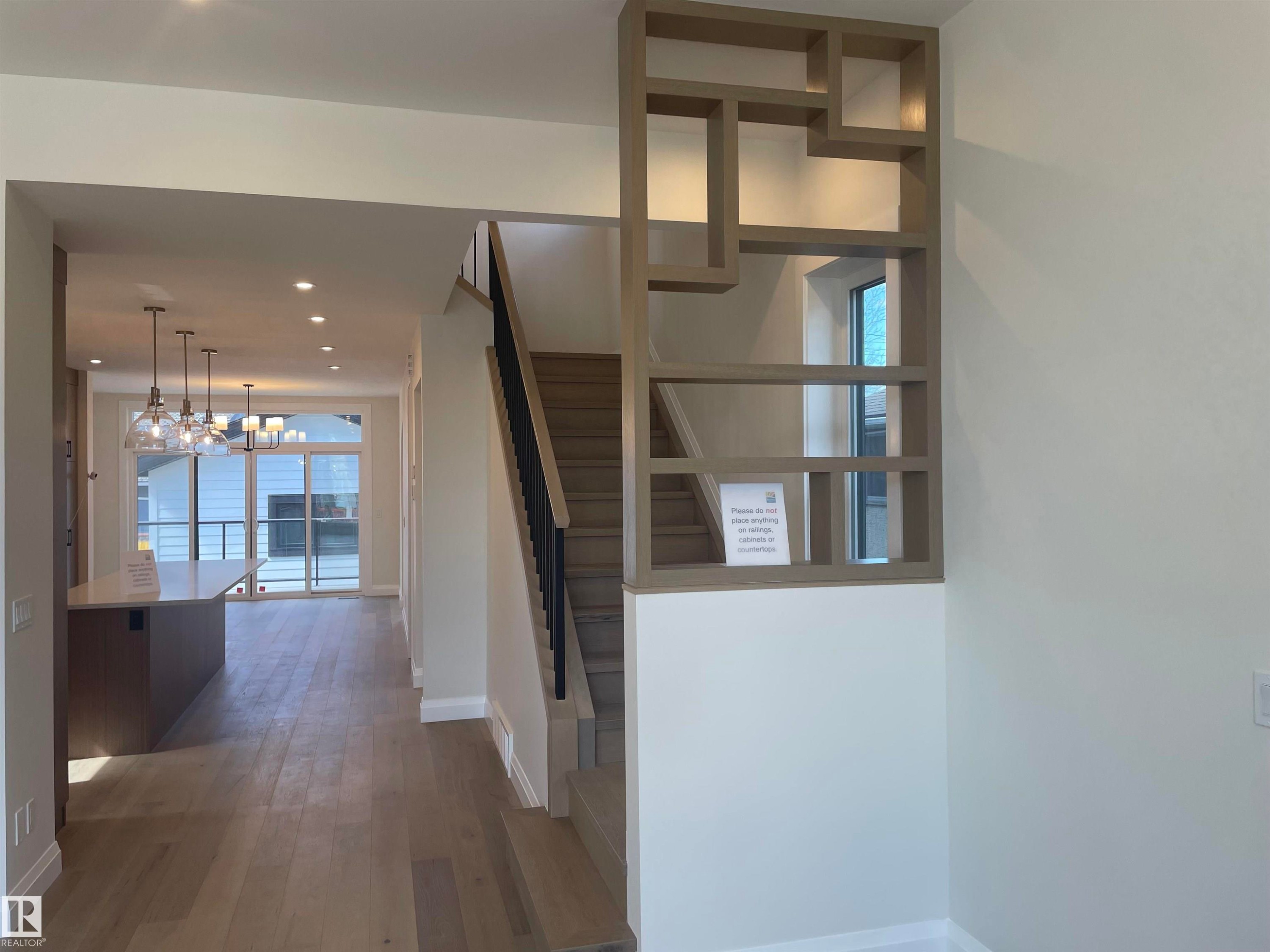 Spacious interior featuring wide-plank wood-finish flooring, a contemporary staircase with black metal balusters, and recessed ceiling lighting - 14344 92A Avenue, Edmonton, AB - Indoor Photo Showing Other Room
