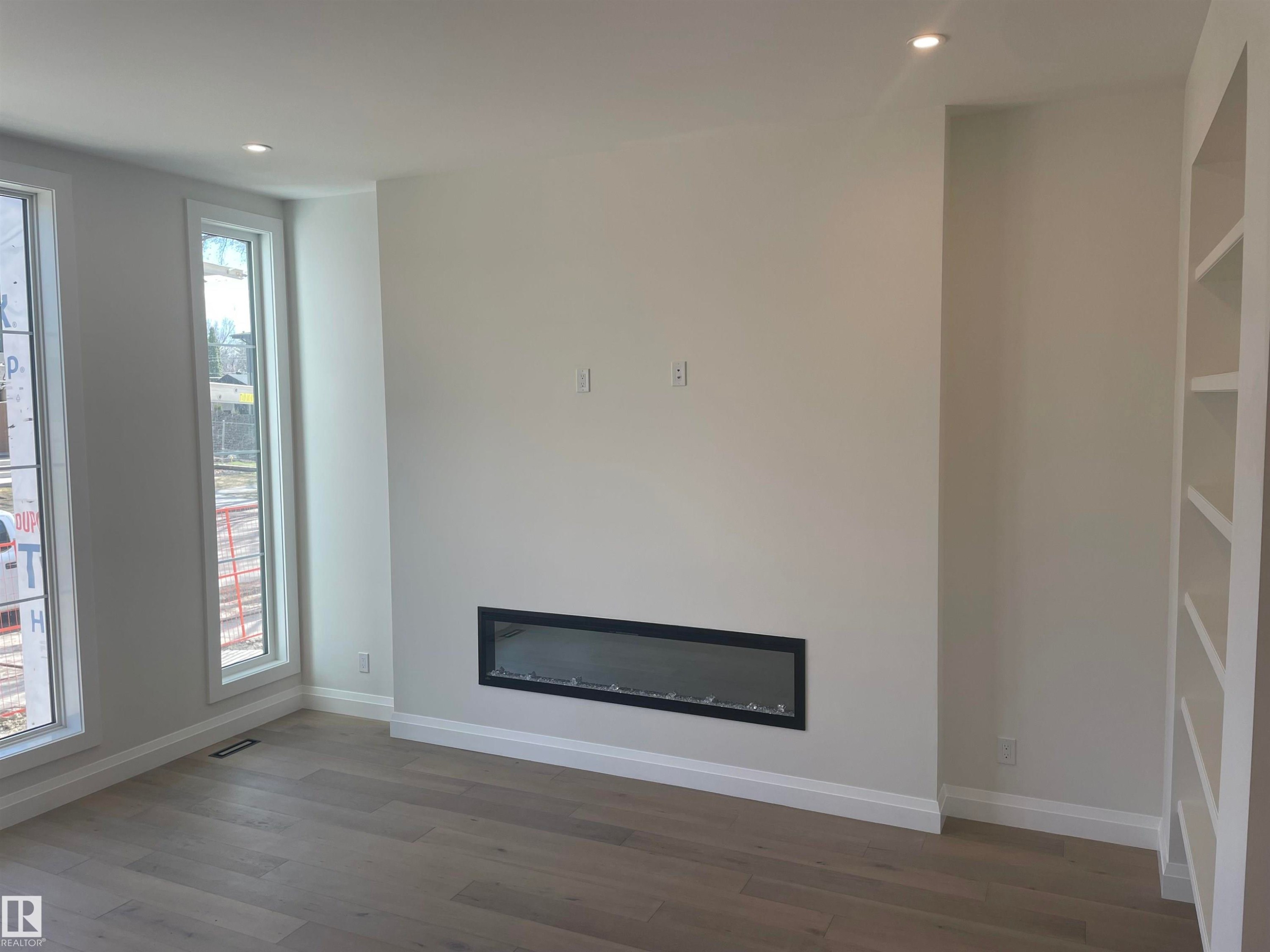 Entryway featuring a decorative built-in shelving unit, hardwood flooring, and a modern staircase with dark iron balusters - 14344 92A Avenue, Edmonton, AB - Indoor Photo Showing Other Room
