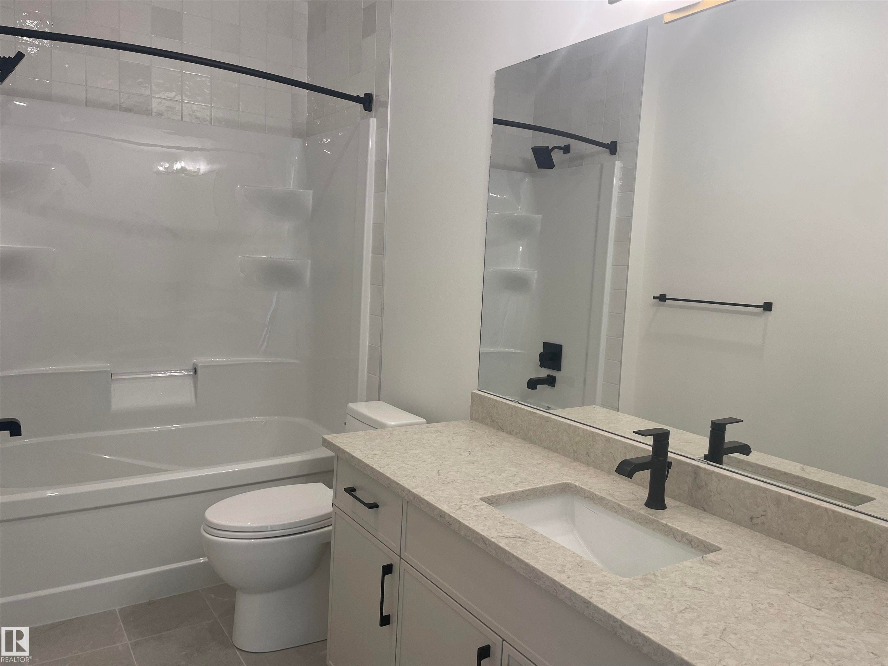 Bathroom featuring a full vanity with a light-toned countertop, an integrated sink, and matte black fixtures - 14344 92A Avenue, Edmonton, AB - Indoor Photo Showing Bathroom