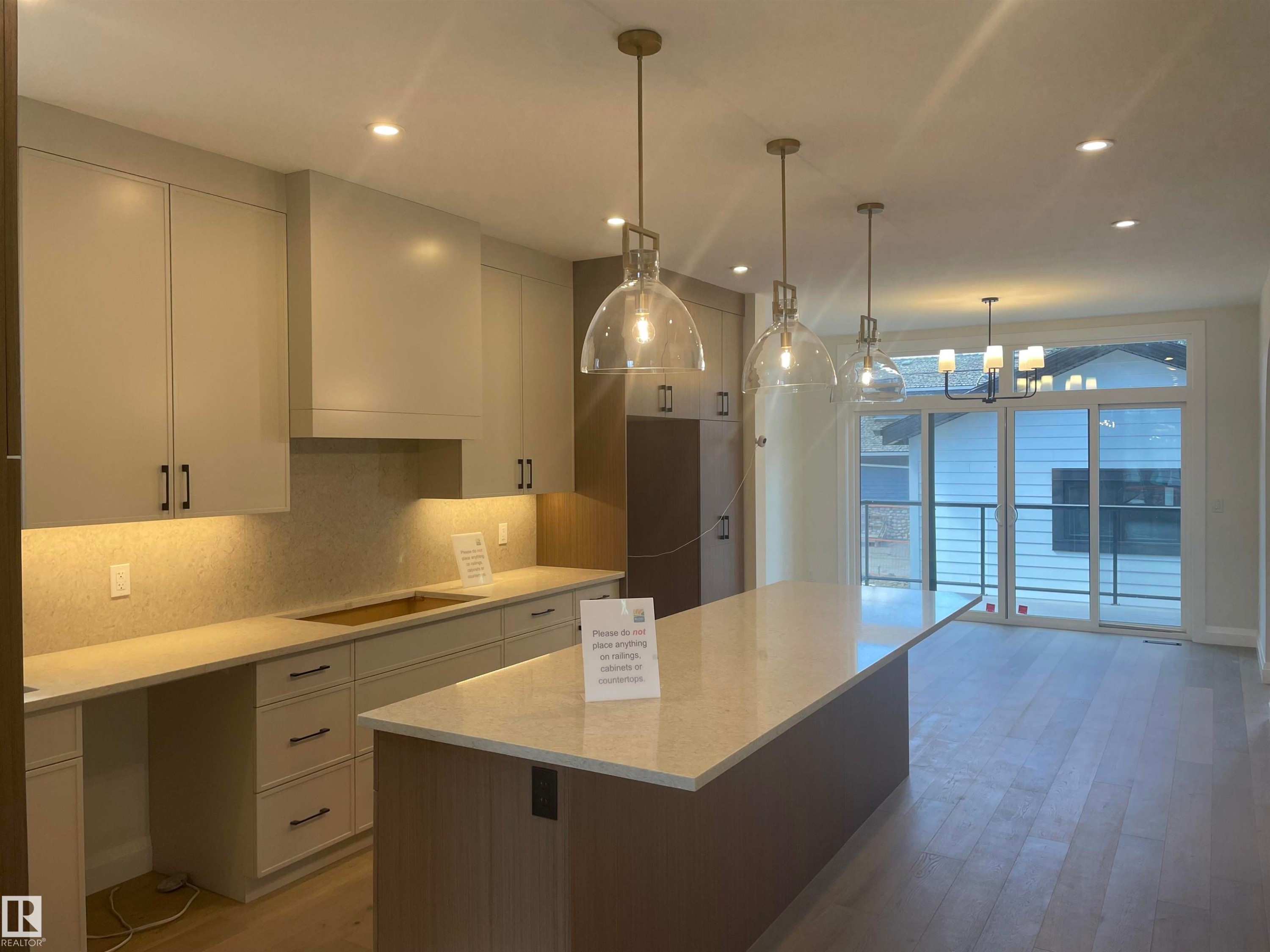 Contemporary kitchen featuring light-toned cabinetry, a large center island with a light countertop, and integrated under-cabinet lighting - 14344 92A Avenue, Edmonton, AB - Indoor Photo Showing Kitchen